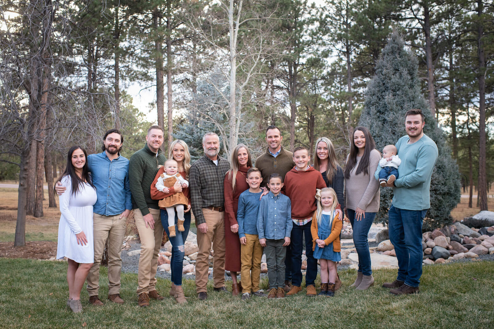 A large extended family stands in a forest smiling