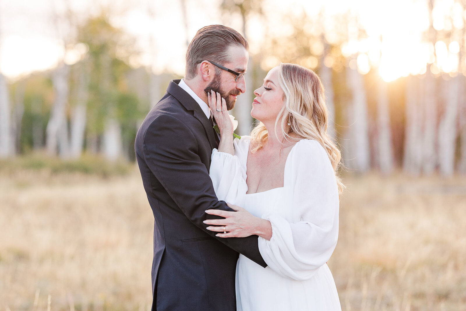 Bride gently holds grooms chin to kiss him during their sunset images in Montrose Colorado