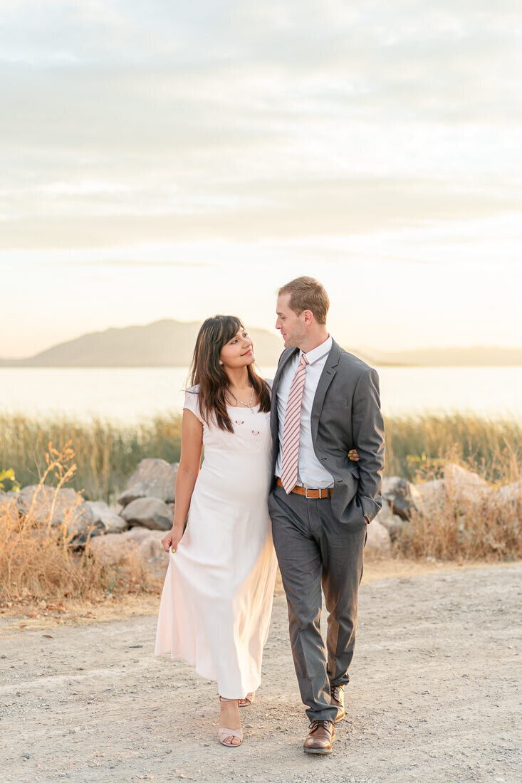 Utah engagement photography of an engaged couple walking near the shore of Utah Lake at sunset in the Fall