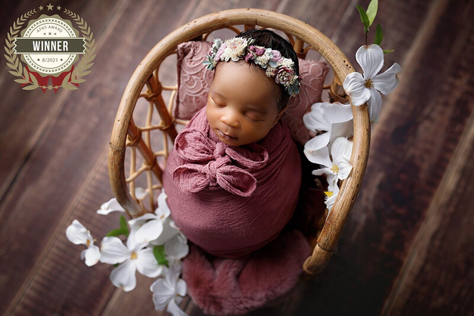 Close-up of a sleeping newborn in a basket with flowers