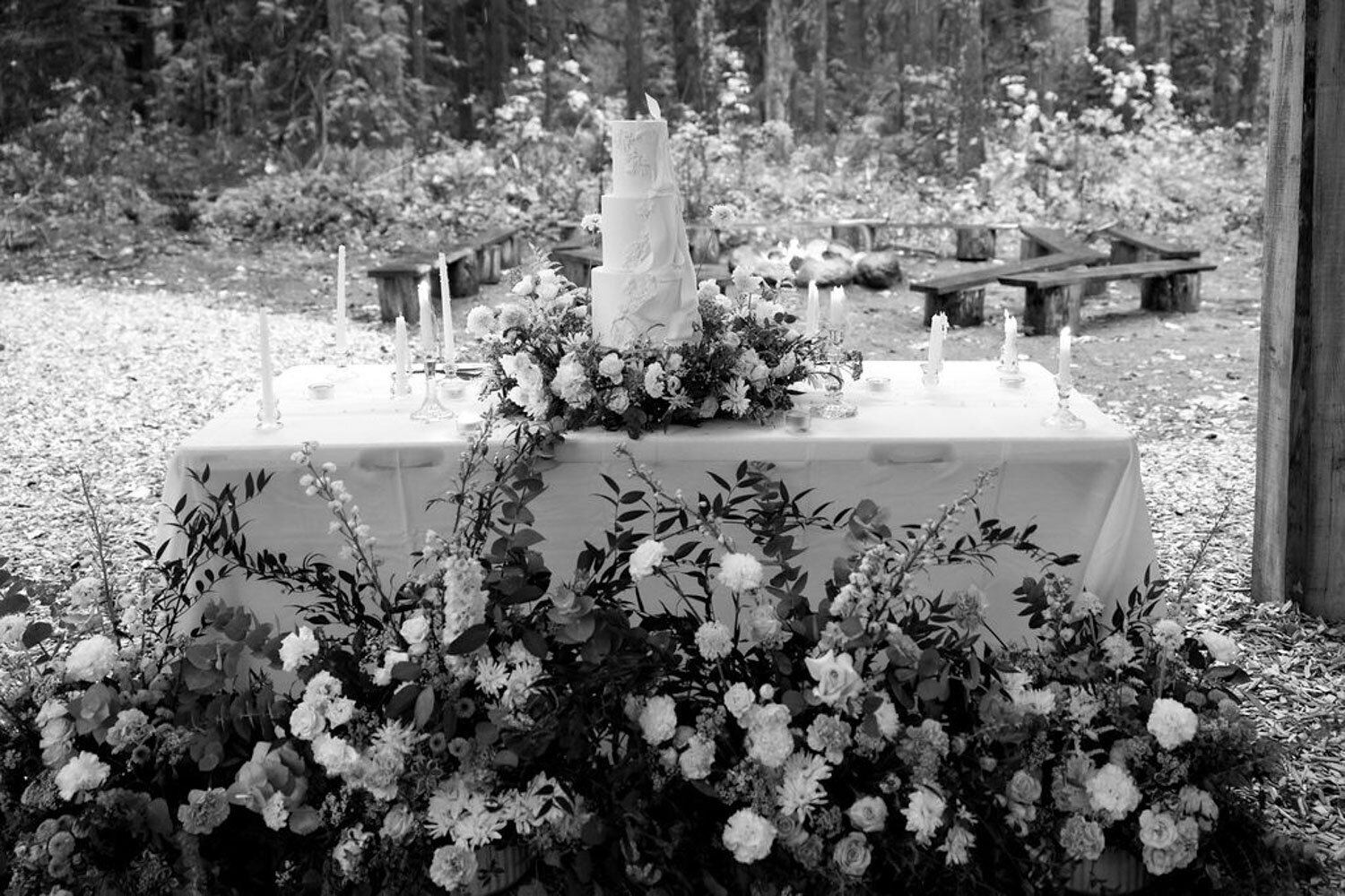 Elegant white wedding cake surrounded by lush white flowers