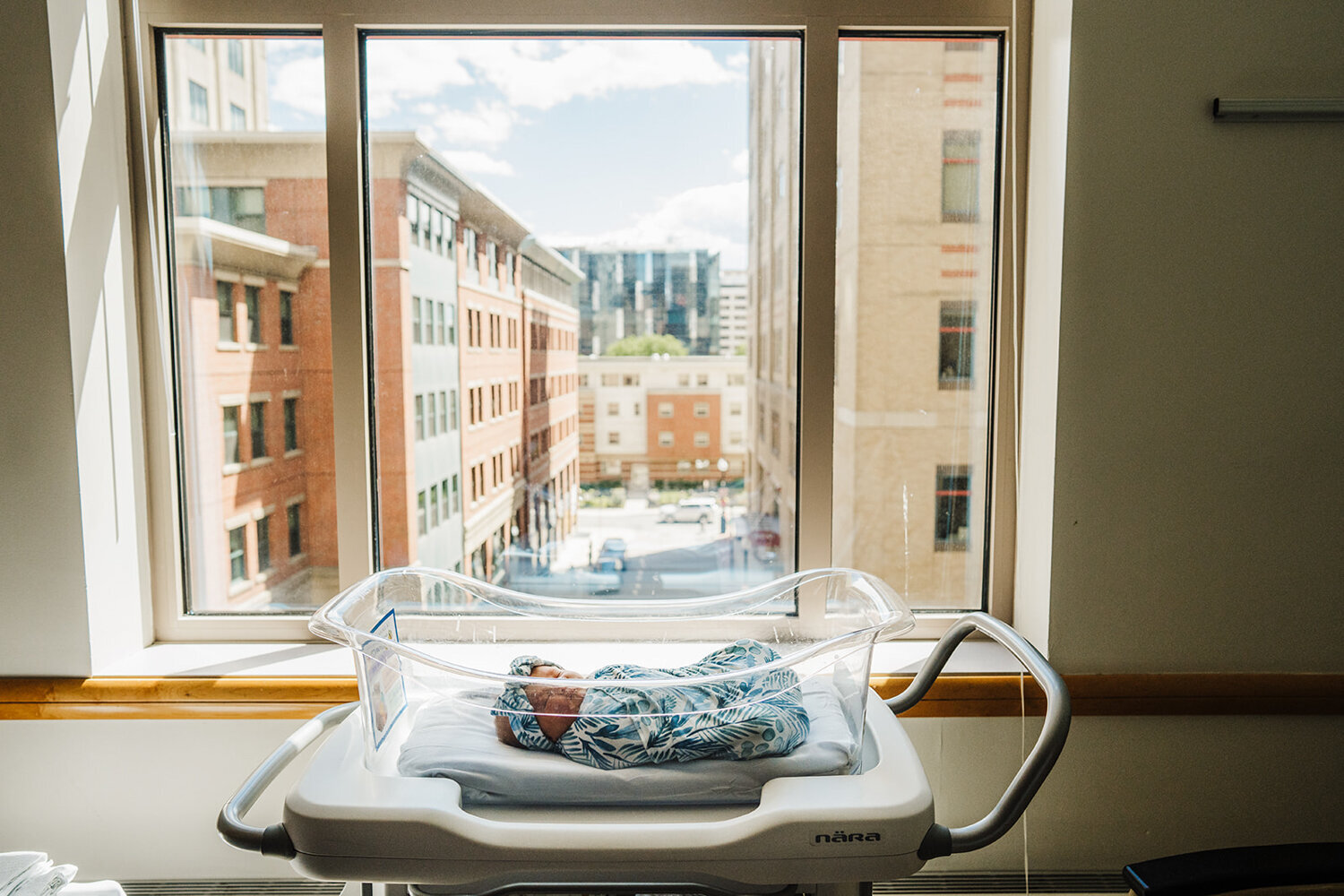 baby lies in bassinet in front of boston hospital window
