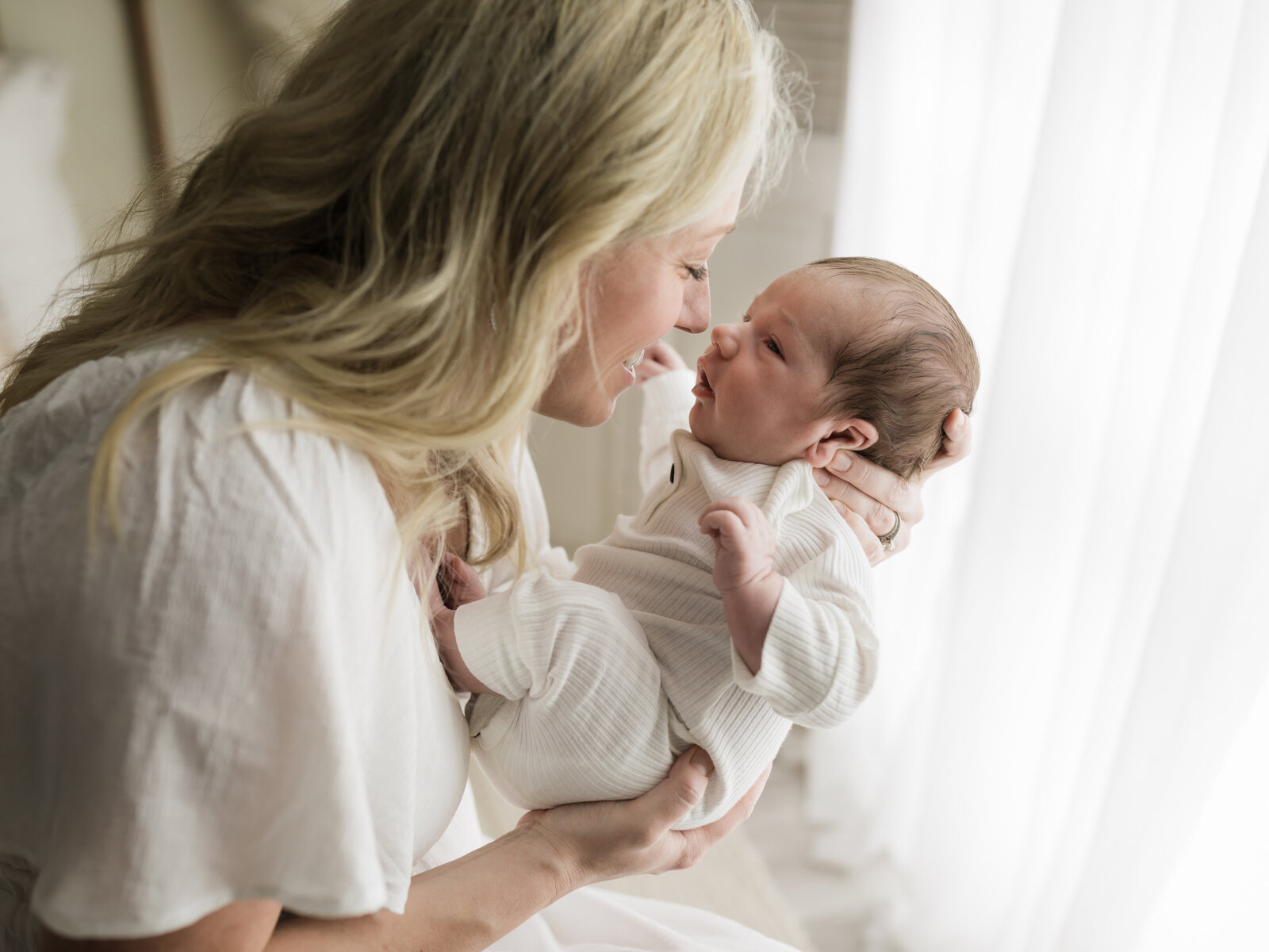 mom holding newborn baby boy in white outfit for studio newborn portraits cleveland newborn photographer