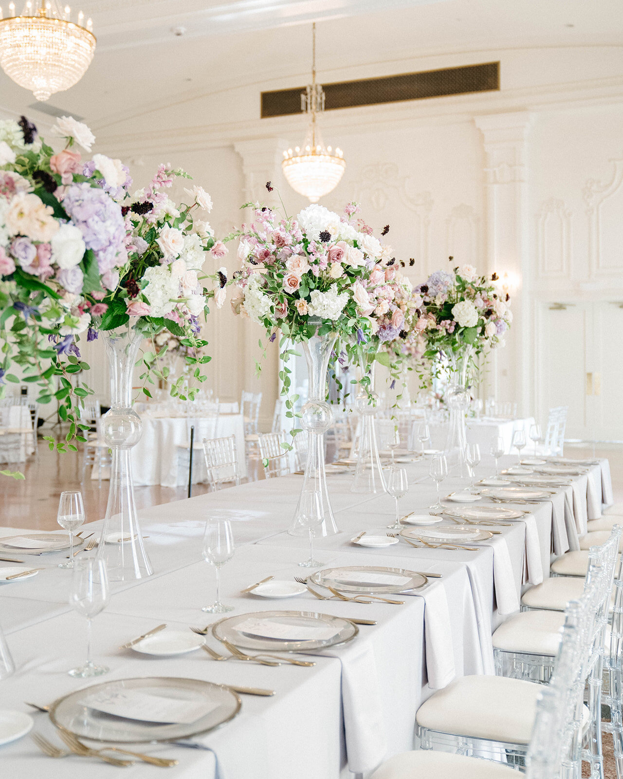 Large floral arrangements line a long table in the ballroom at the Mayo Hotel in Tulsa.