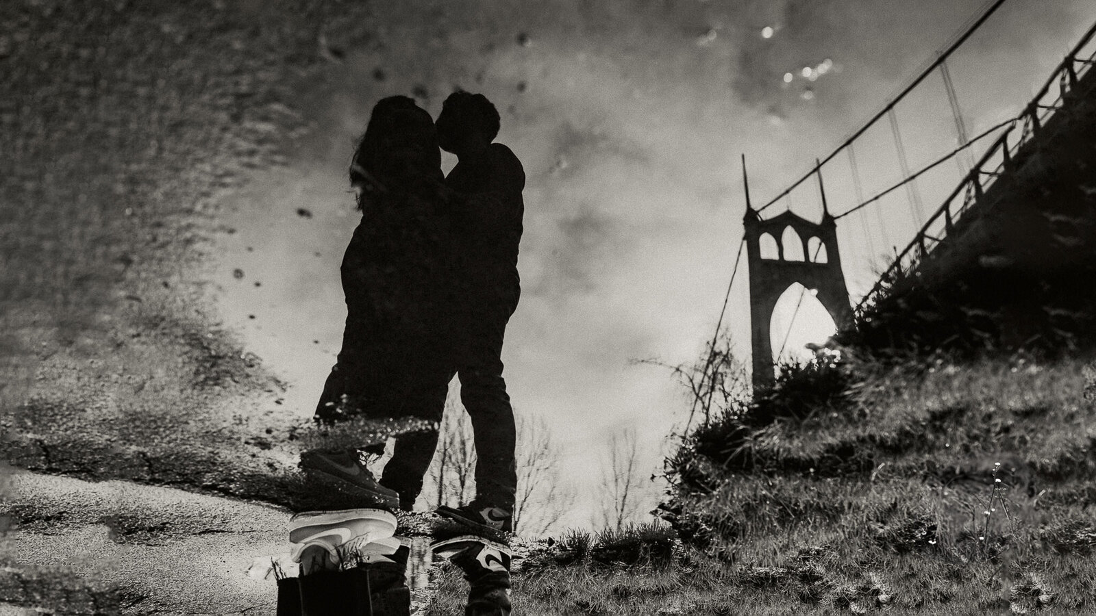 Engagement session puddle reflection of couple kissing and bridge