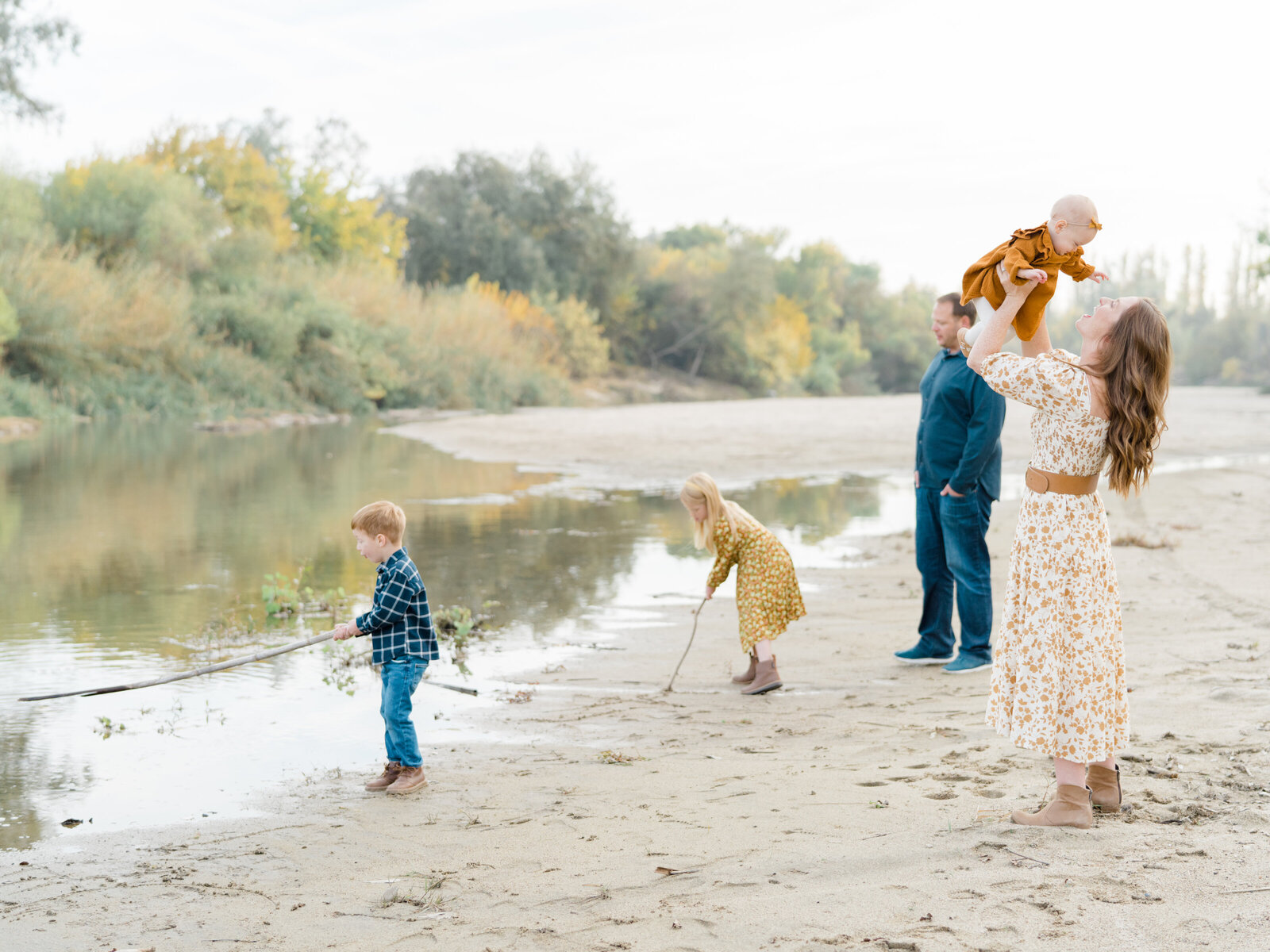 family of five beside a stream and drawing pictures in the sand with sticks