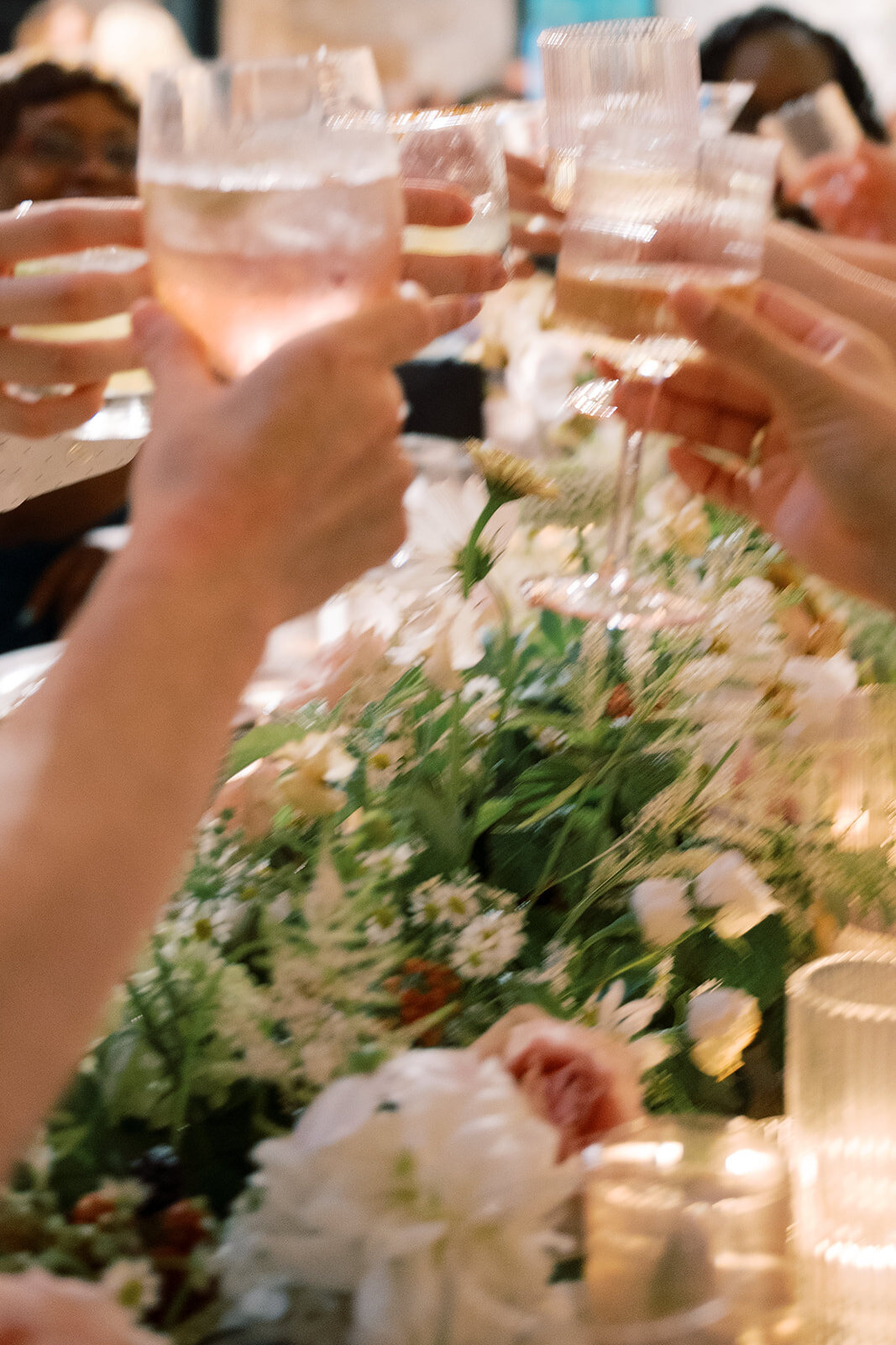 Guests giving cheers at reception over floral centerpieces.