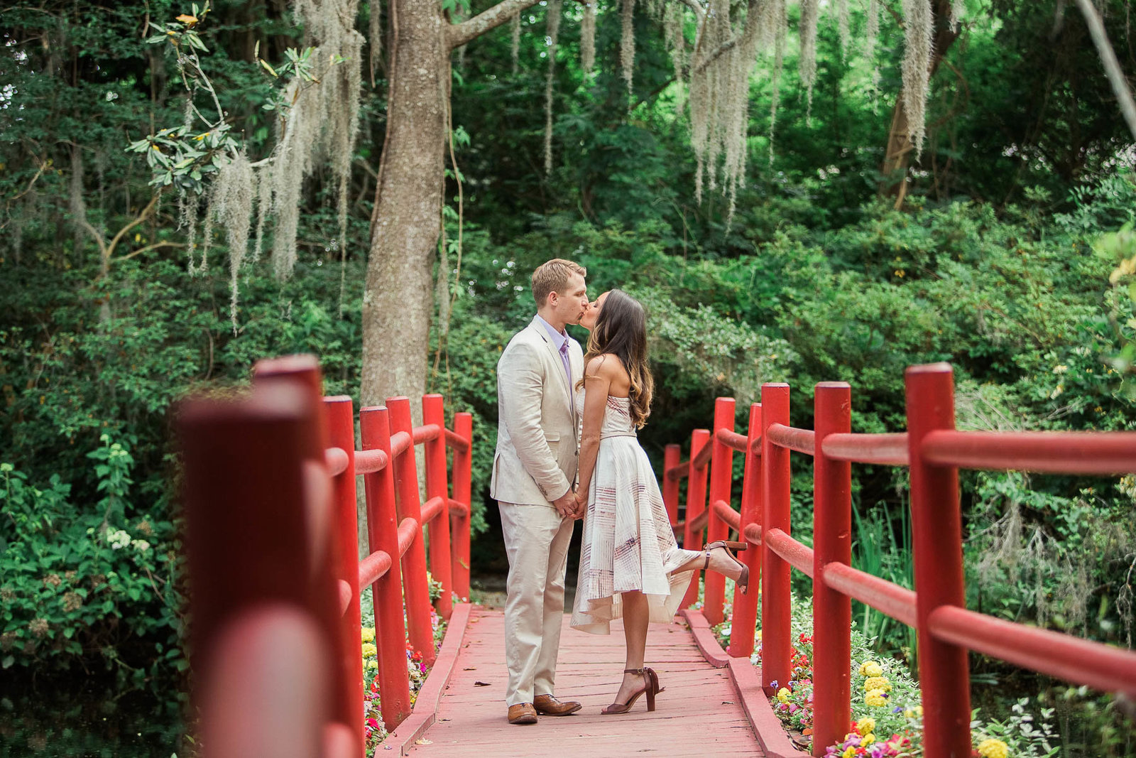 Engaged couple stand on a red bridge, Magnolia Plantation, Charleston, South Carolina