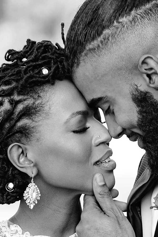 A  black couple in love bows their heads together on their wedding day