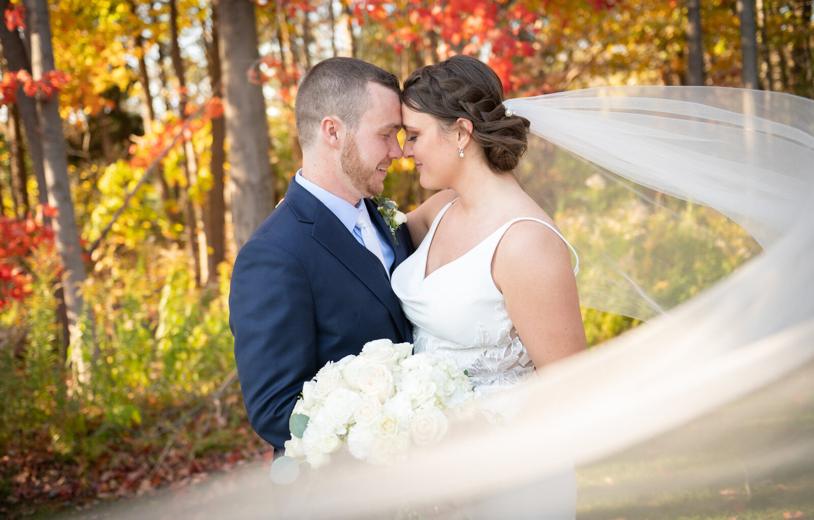 wedding couple put foreheads together as veil encircles them