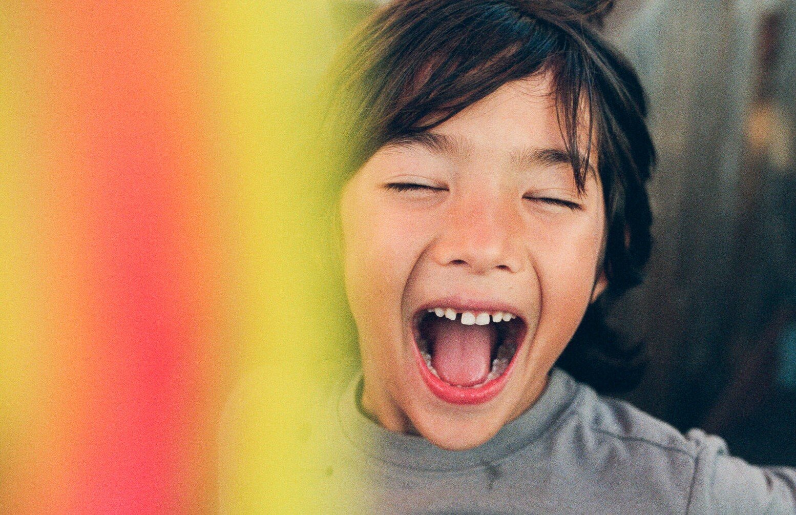 photo of a mixed race child laughing with eyes closed