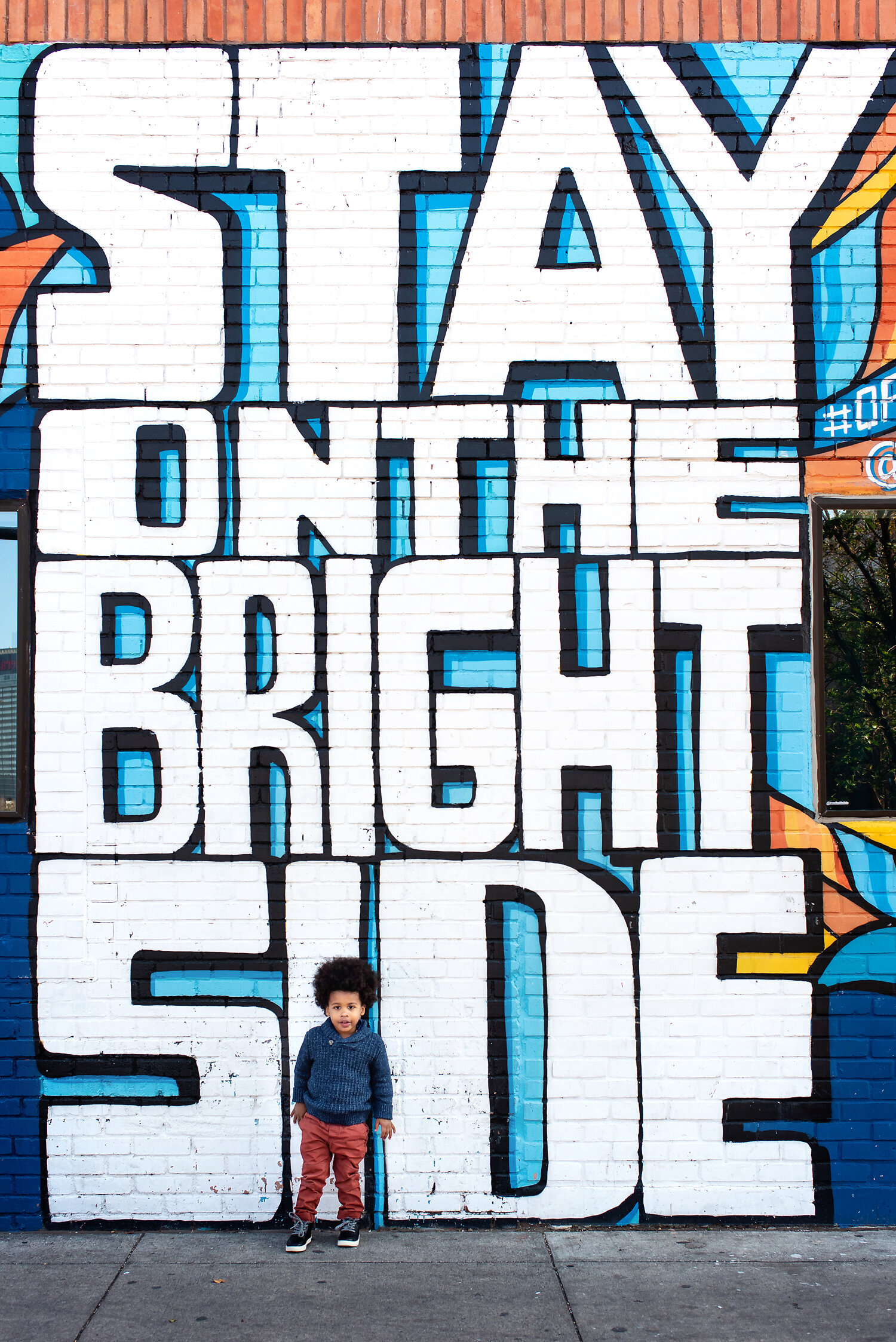 Toddler boy standing in front of a graffiti wall in Dallas, TX.