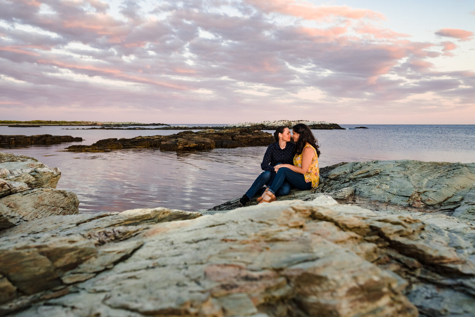 women-sit-on-rocks-at-sunset-newport-engagement-lisa-gilbert-photography