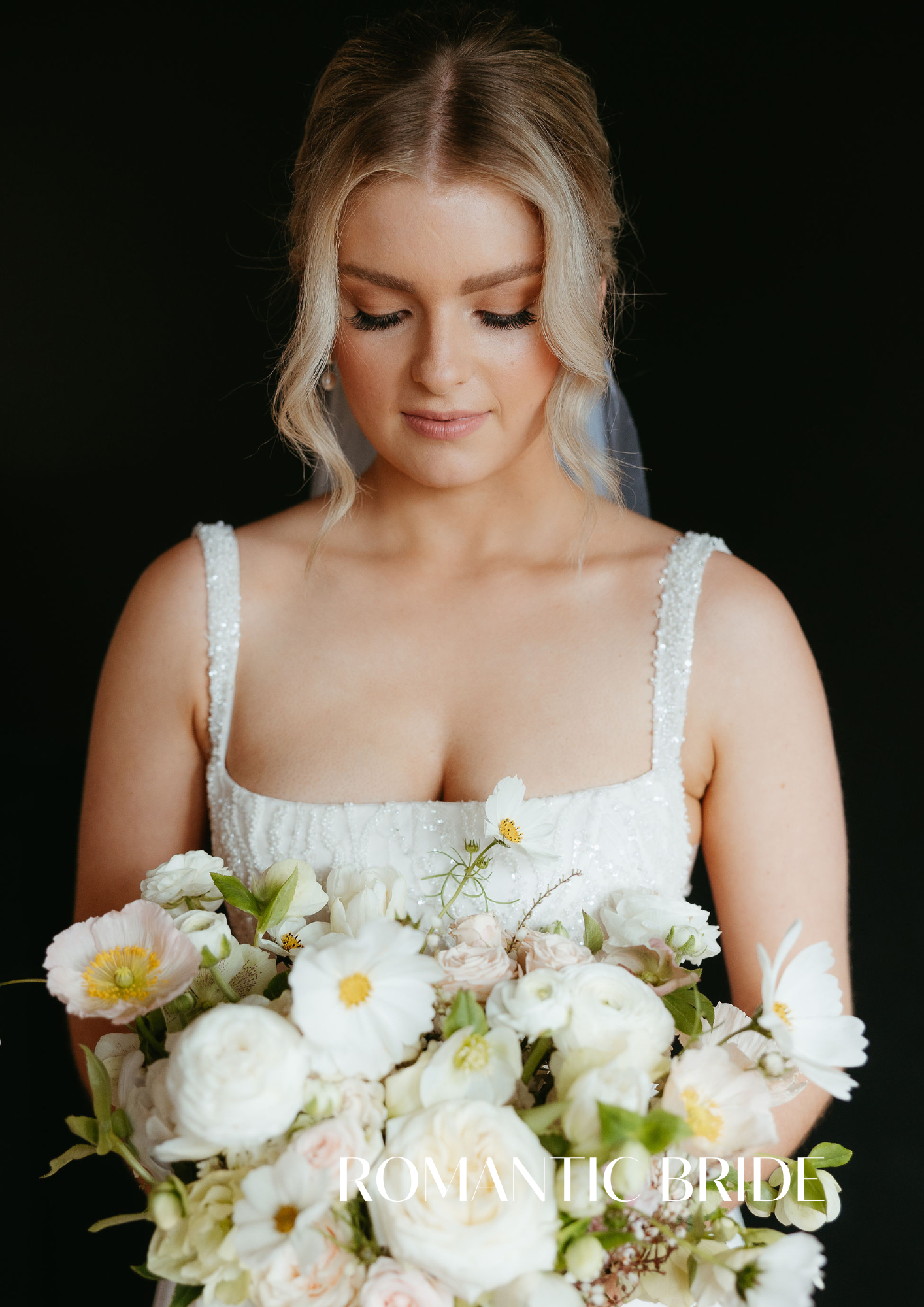 Beautiful Bella Rae Bride Abby looking down at her flowers withe soft gam makeup and textured bun at Bellingdale Farm captured by Chasing Moment Photography