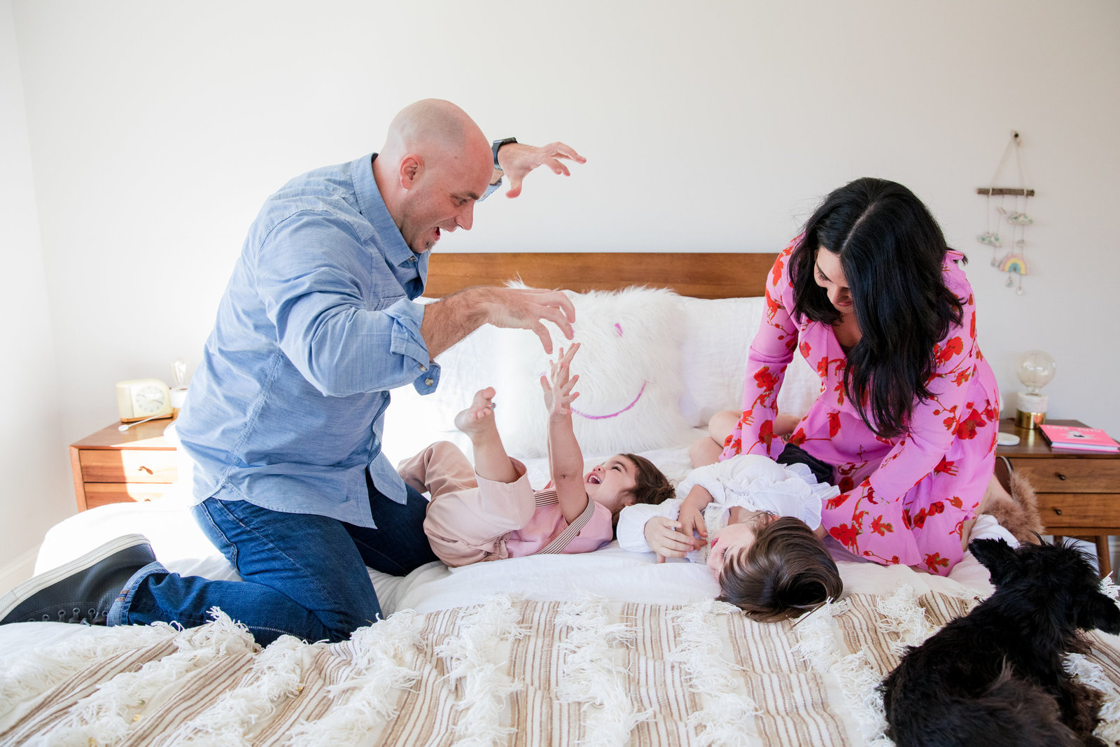 family of four on bed, mom and dad playing with kids