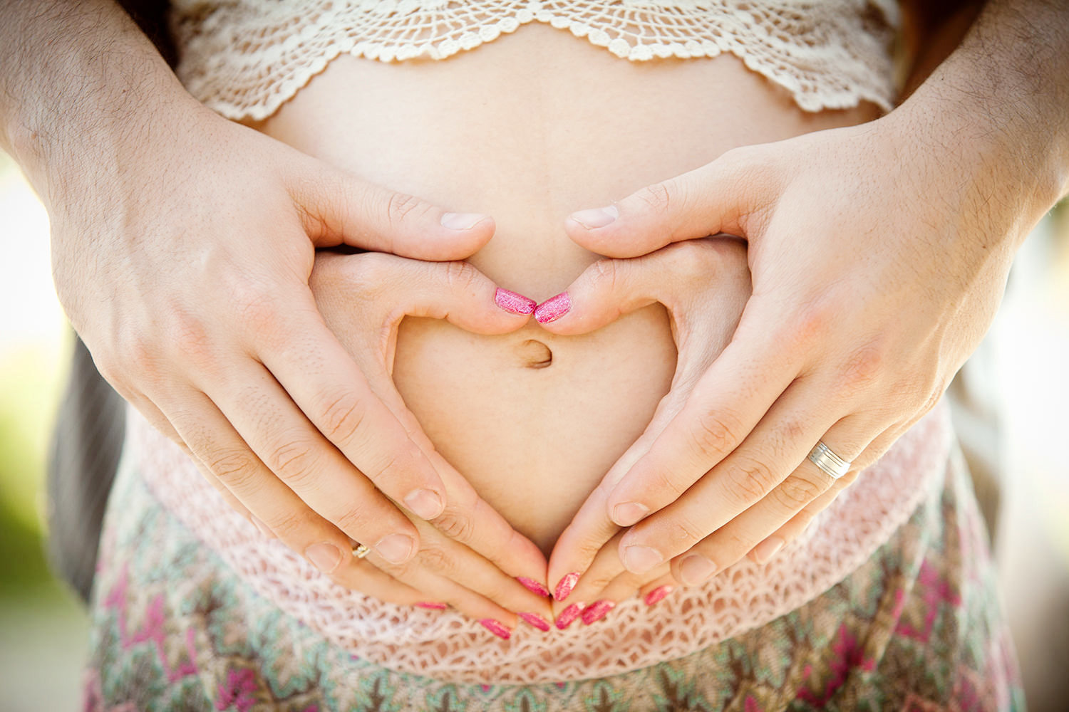 Hands making a heart around pregnant belly during this Maternity Session.