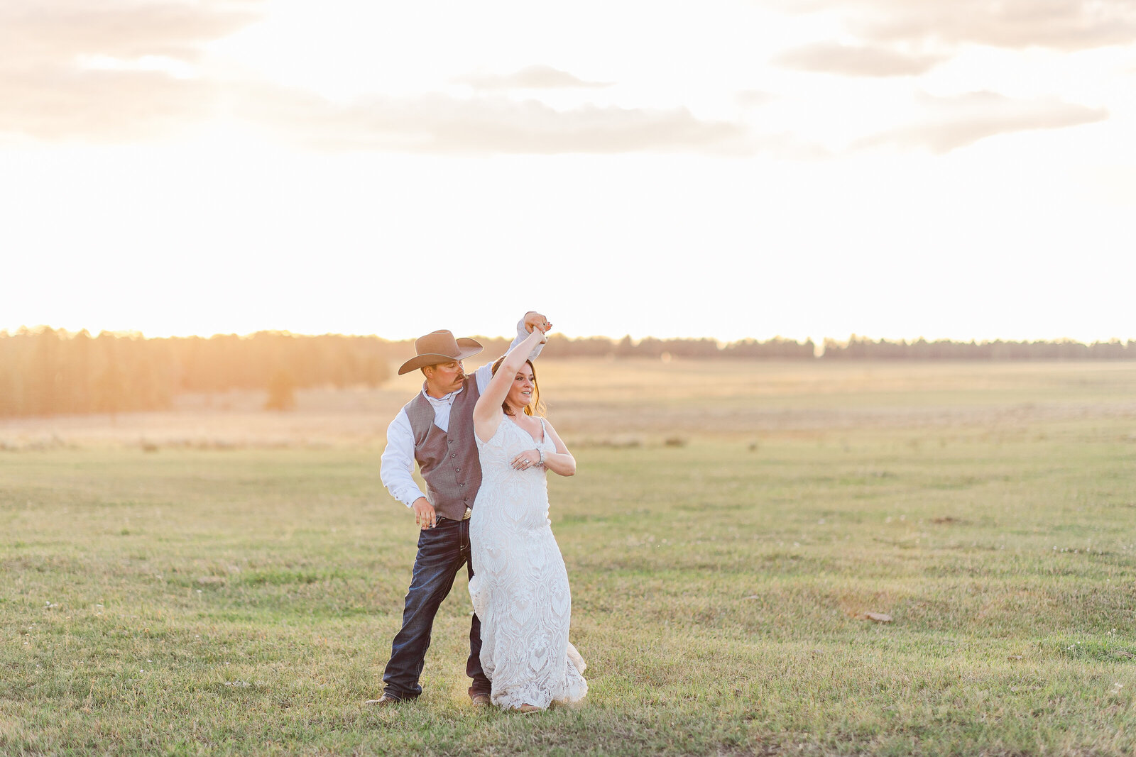 Groom spinning bride in field