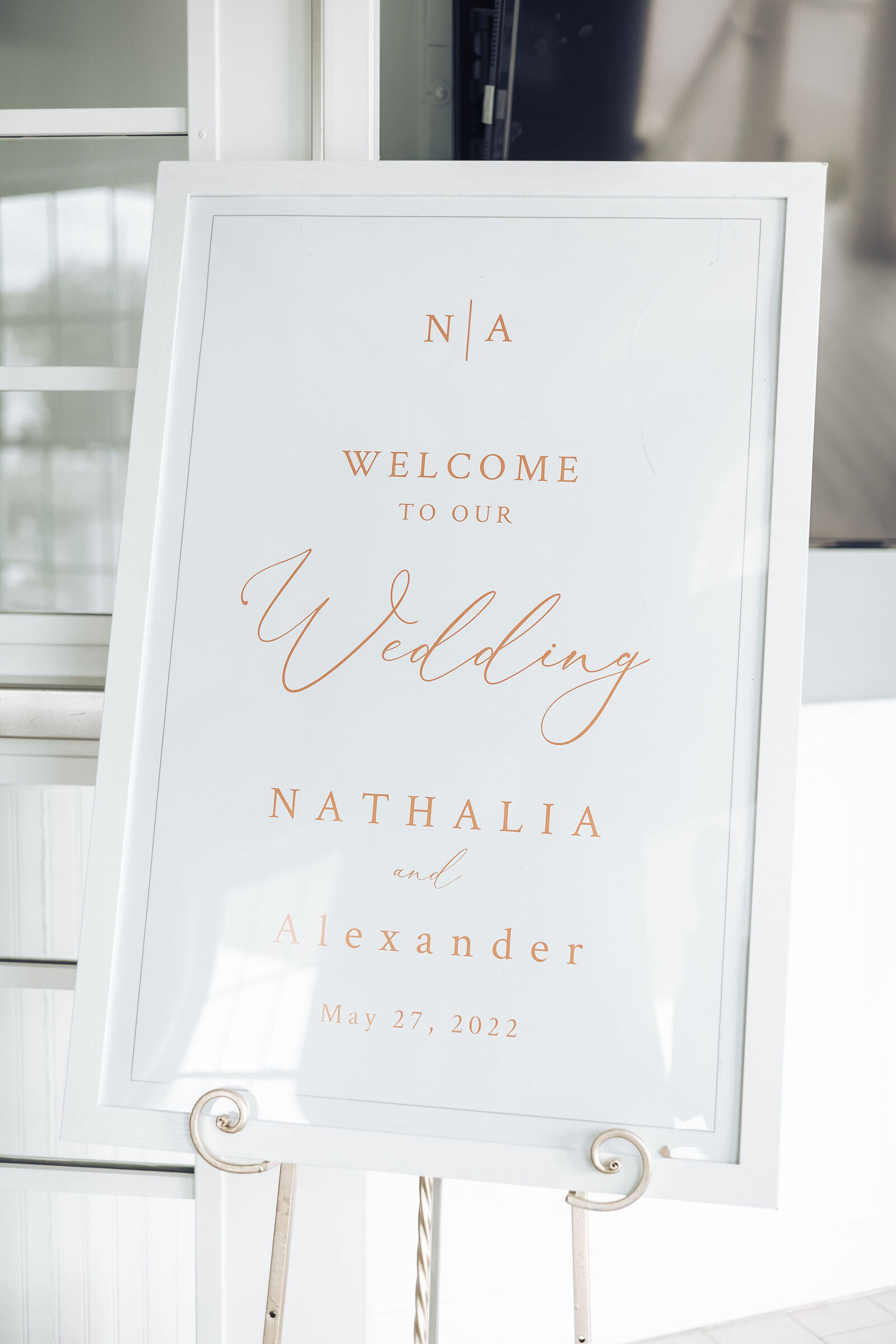 white welcome to our wedding sign with gold text in a white frame