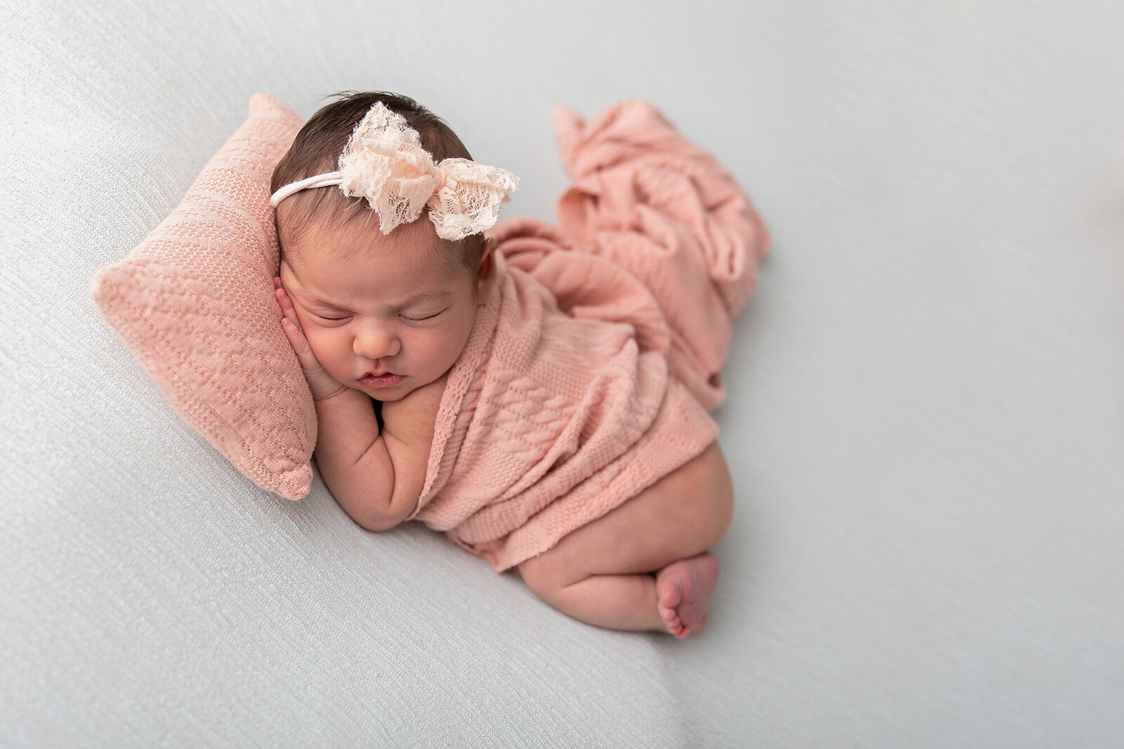 baby in pink sleeping on pink pillow