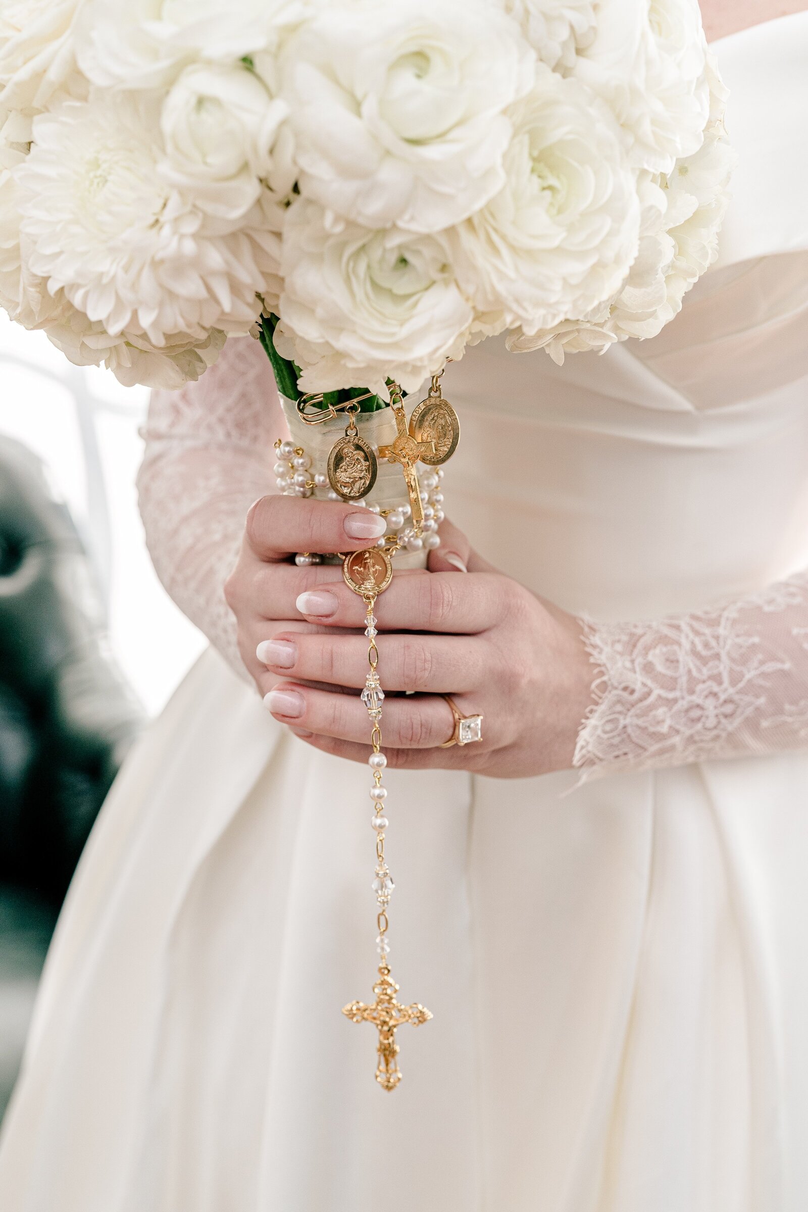 A bride holding her wedding bouquet with a rosary wrapped around the base before her Catholic wedding in Washington DC