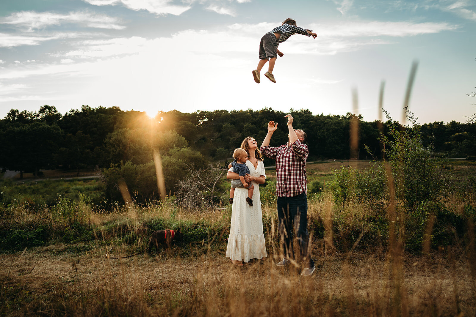 father tosses toddler son high in the air during family pictures in boston