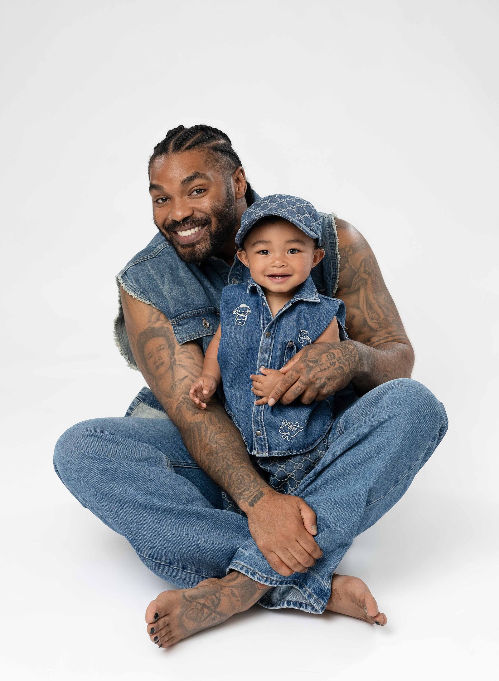 Dad sitting on floor with baby in his lap and both smiling.