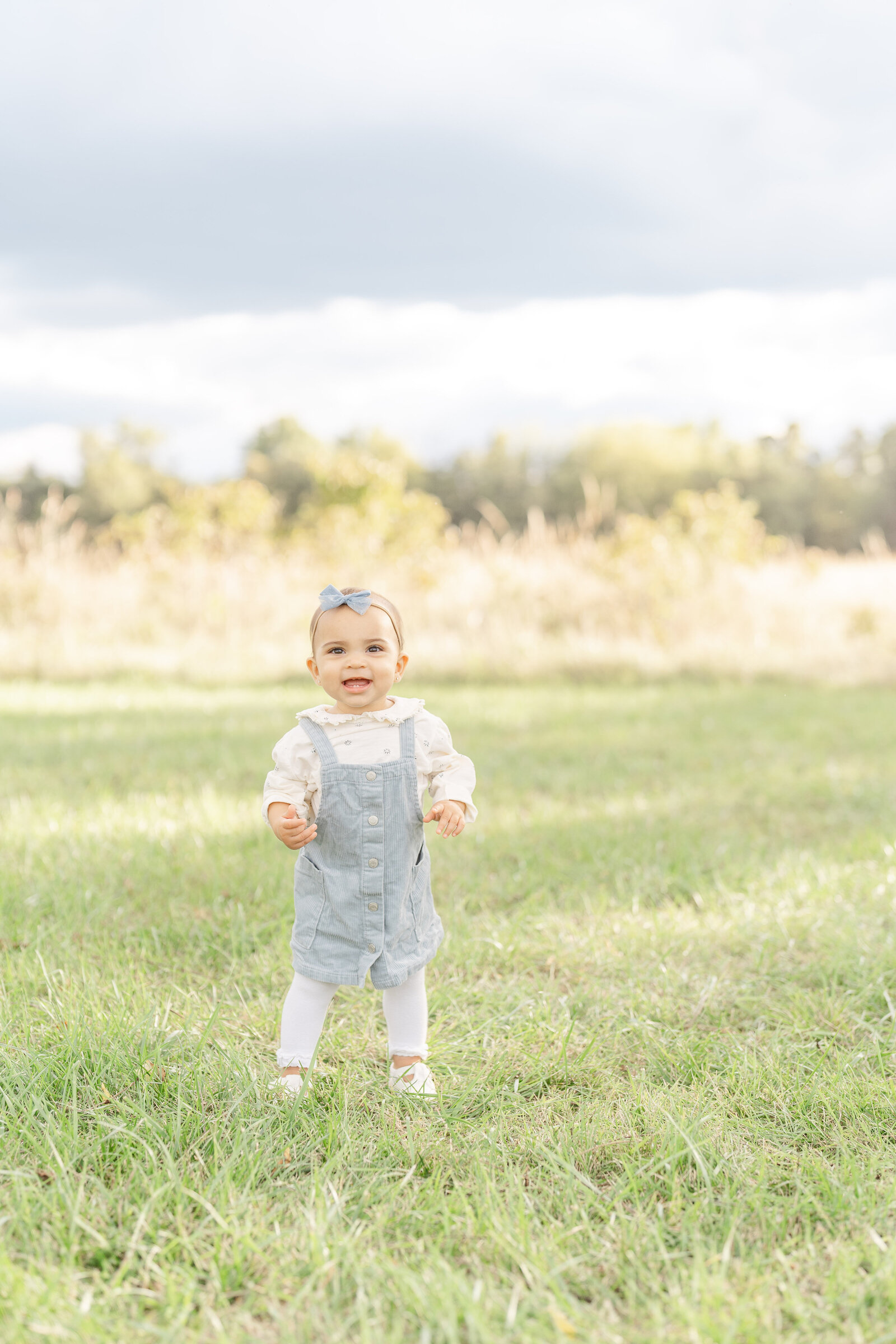 baby standing in a field during family picture in Sterling, VA