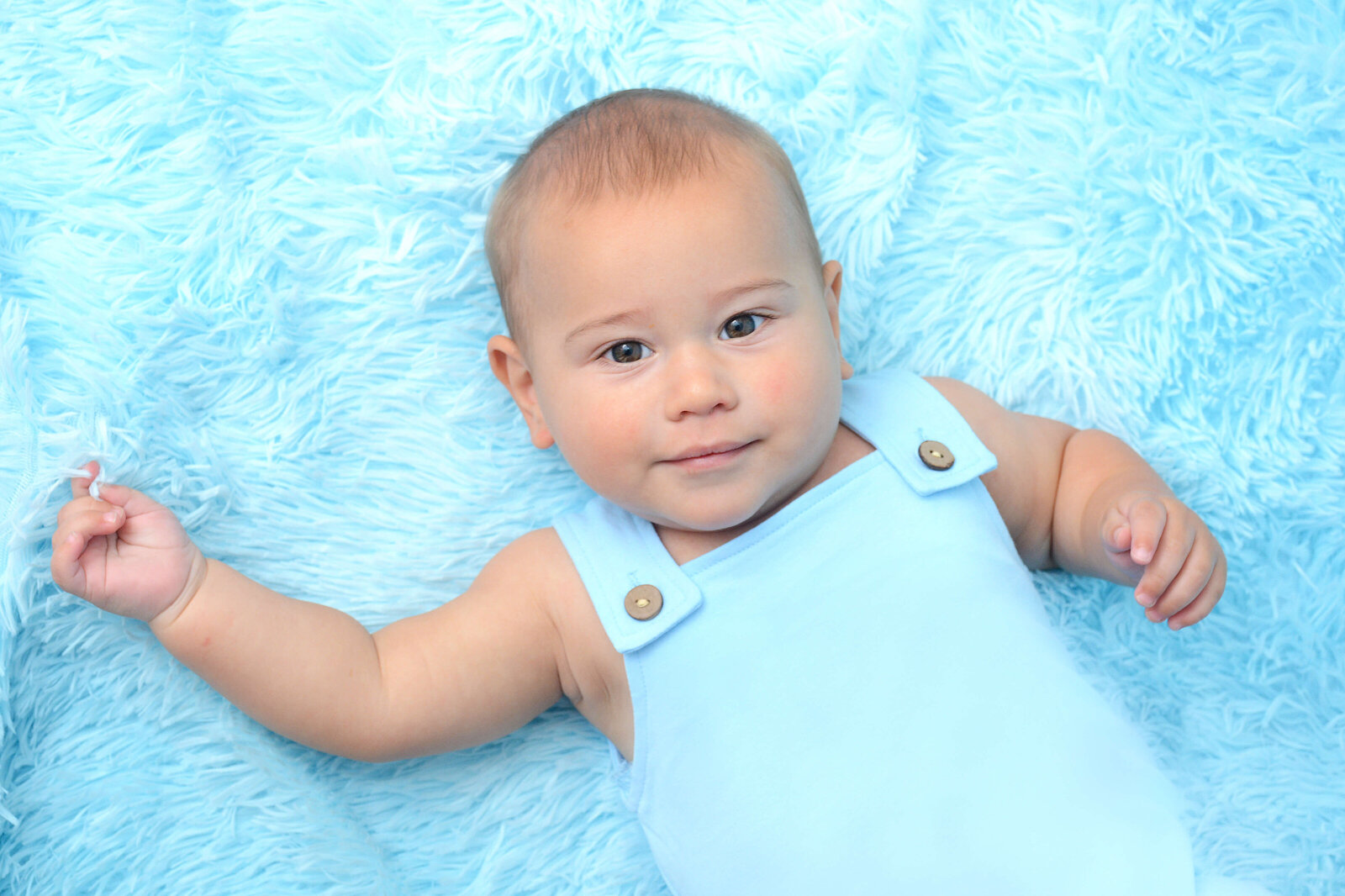 baby smiling on blue blanket