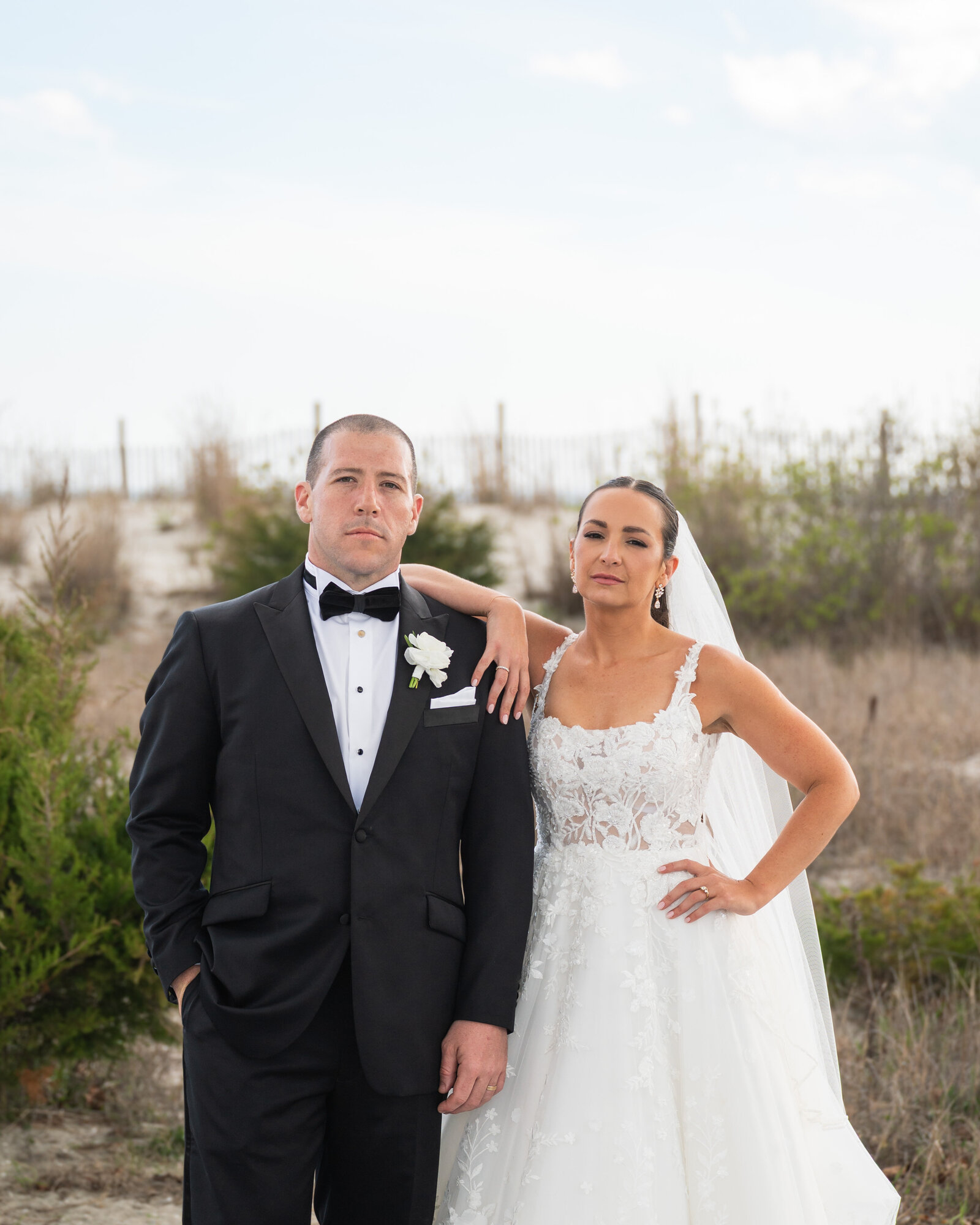 Wedding couple with serious expressions looking at the camera in front of a dune in Cape May NJ