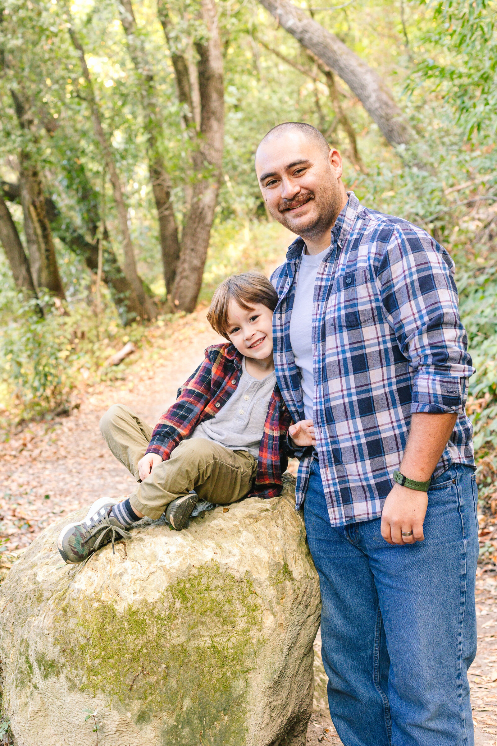 A family of 3 poses for photos in a forest in Santa Cruz, Ca.