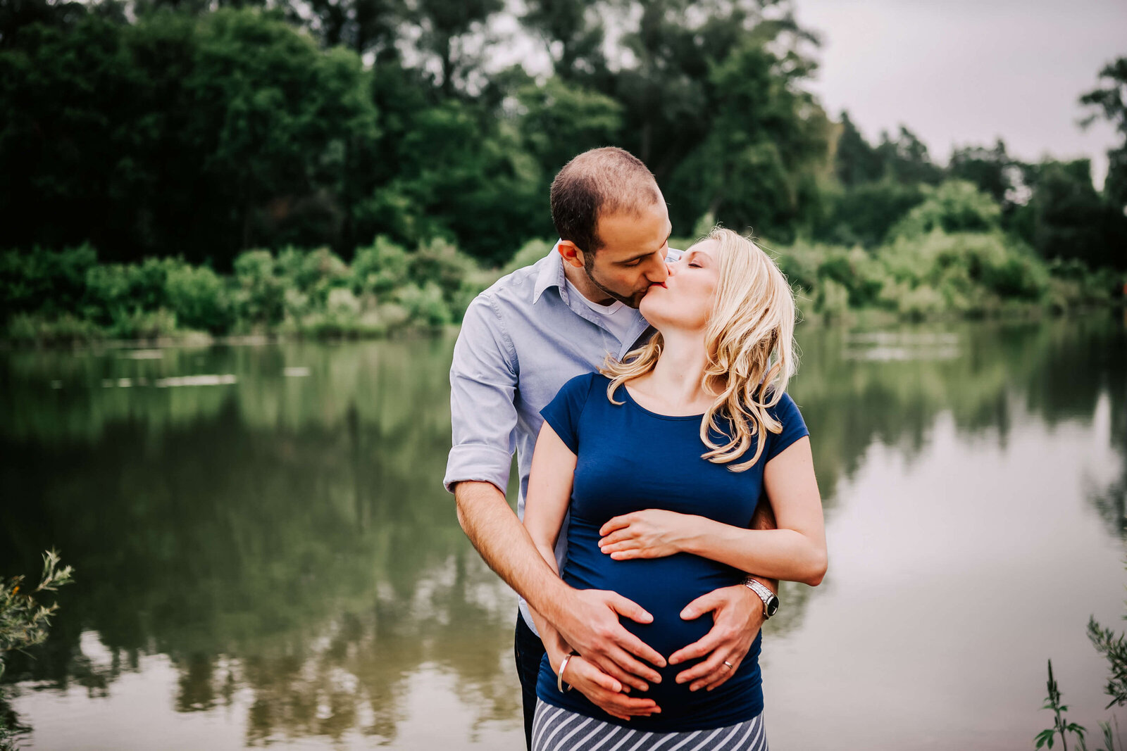 momma to be with husband kissing by the Grand River