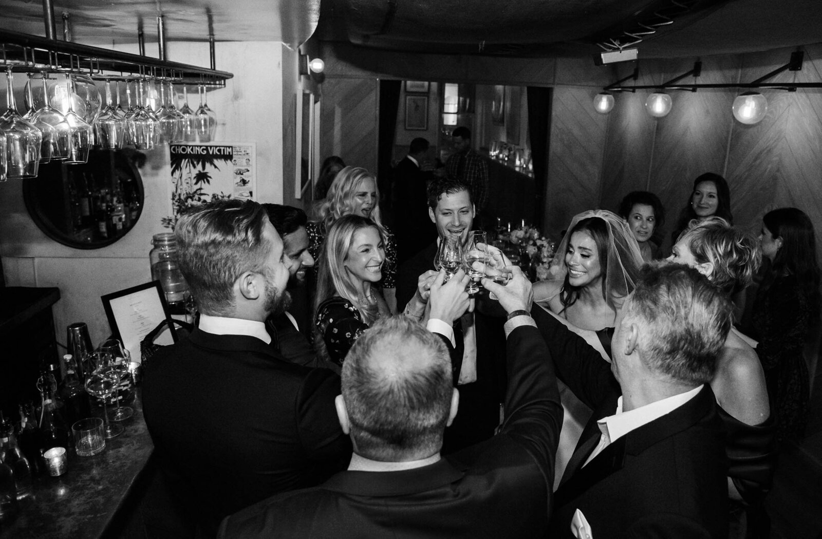 black and whit picture of a family clicking their champagne glass after the microwedding of an attractive bride in her maison signore wedding dress.