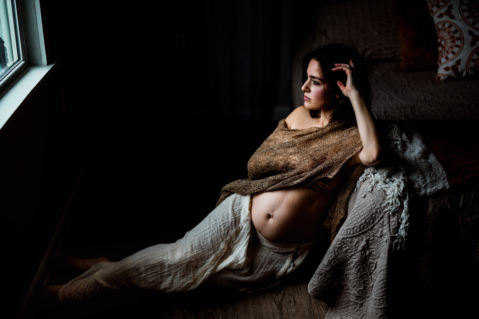 Pregnant mother sitting on the floor, looking out the window