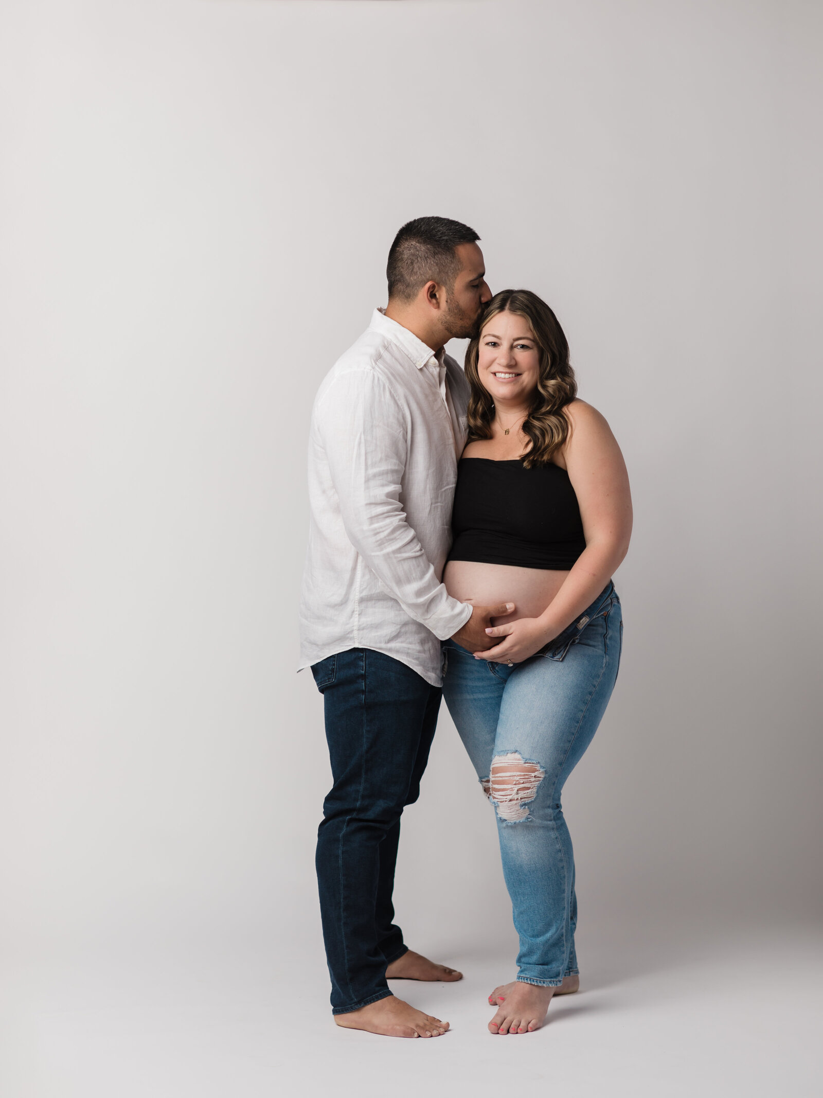 husband and pregnant wife holding belly for studio maternity photoshoot