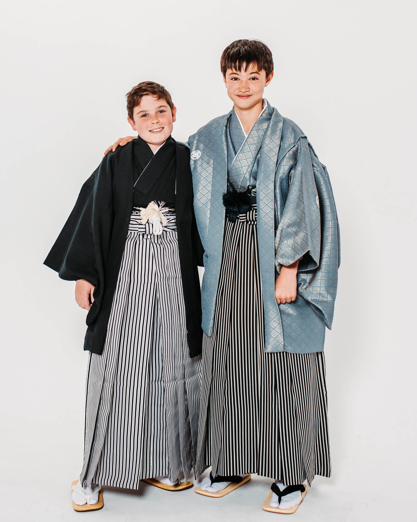Two boys in montsuki hakama standing side by side, smiling in traditional graduation attire | 卒業式 紋付袴 男の子 二人 記念写真