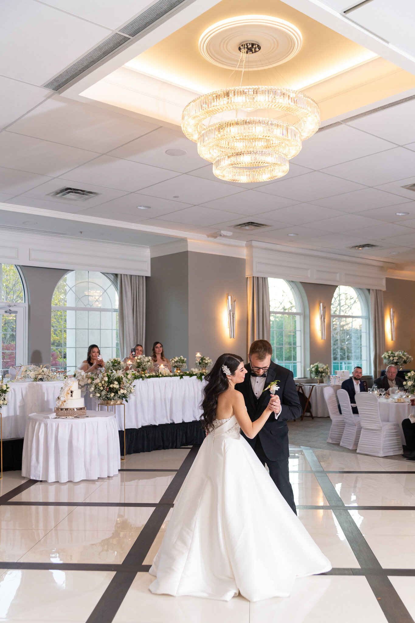 bride and groom sharing their first dance under a chandelier