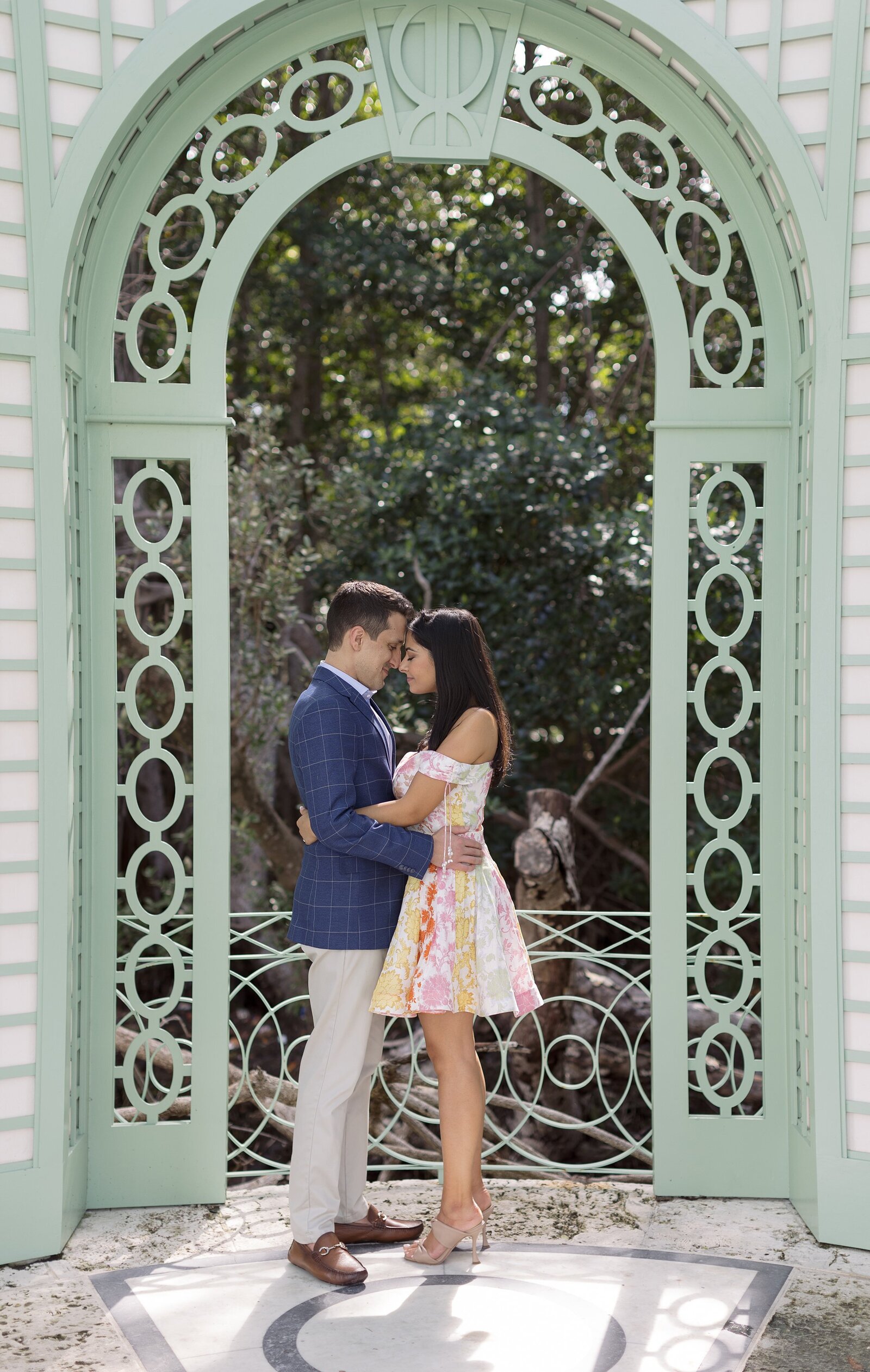 Couple embrace while standing under a green archway at Vizcaya, Miami.