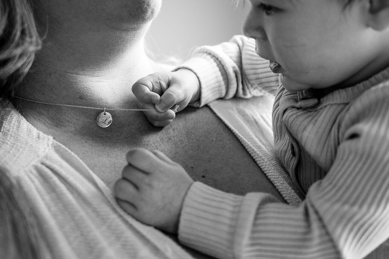baby grabs mothers necklace with chubby fingers