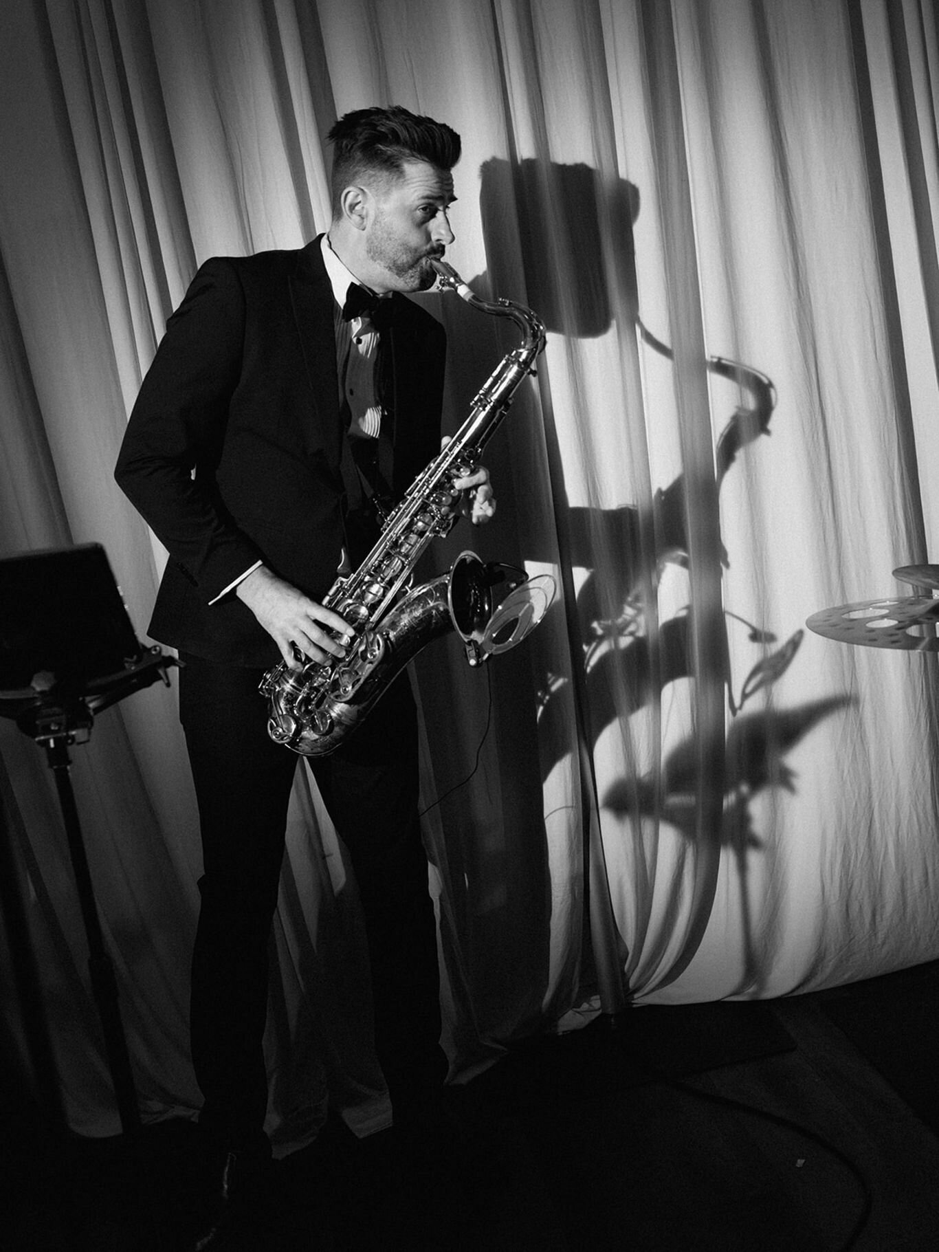 Saxophonist performing live at a wedding reception, captured in black and white.