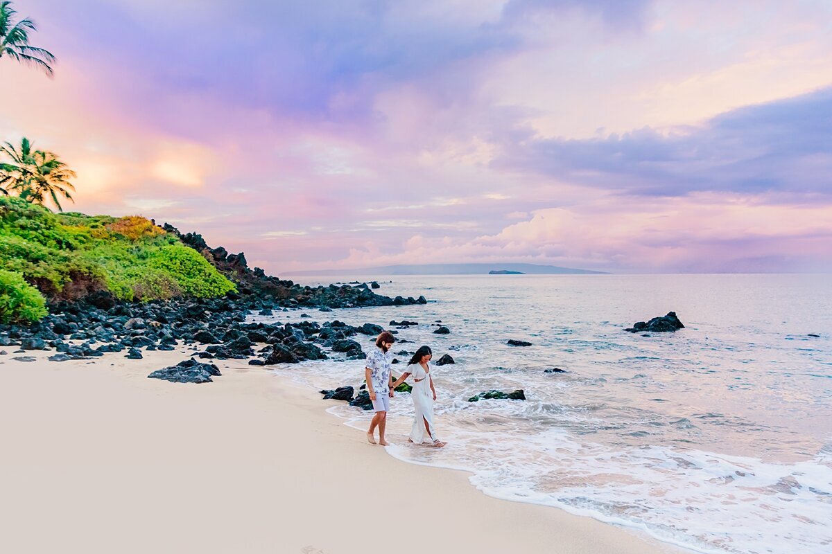 purple and pastel skies beyond a maui beach as the water brushes up against the shore