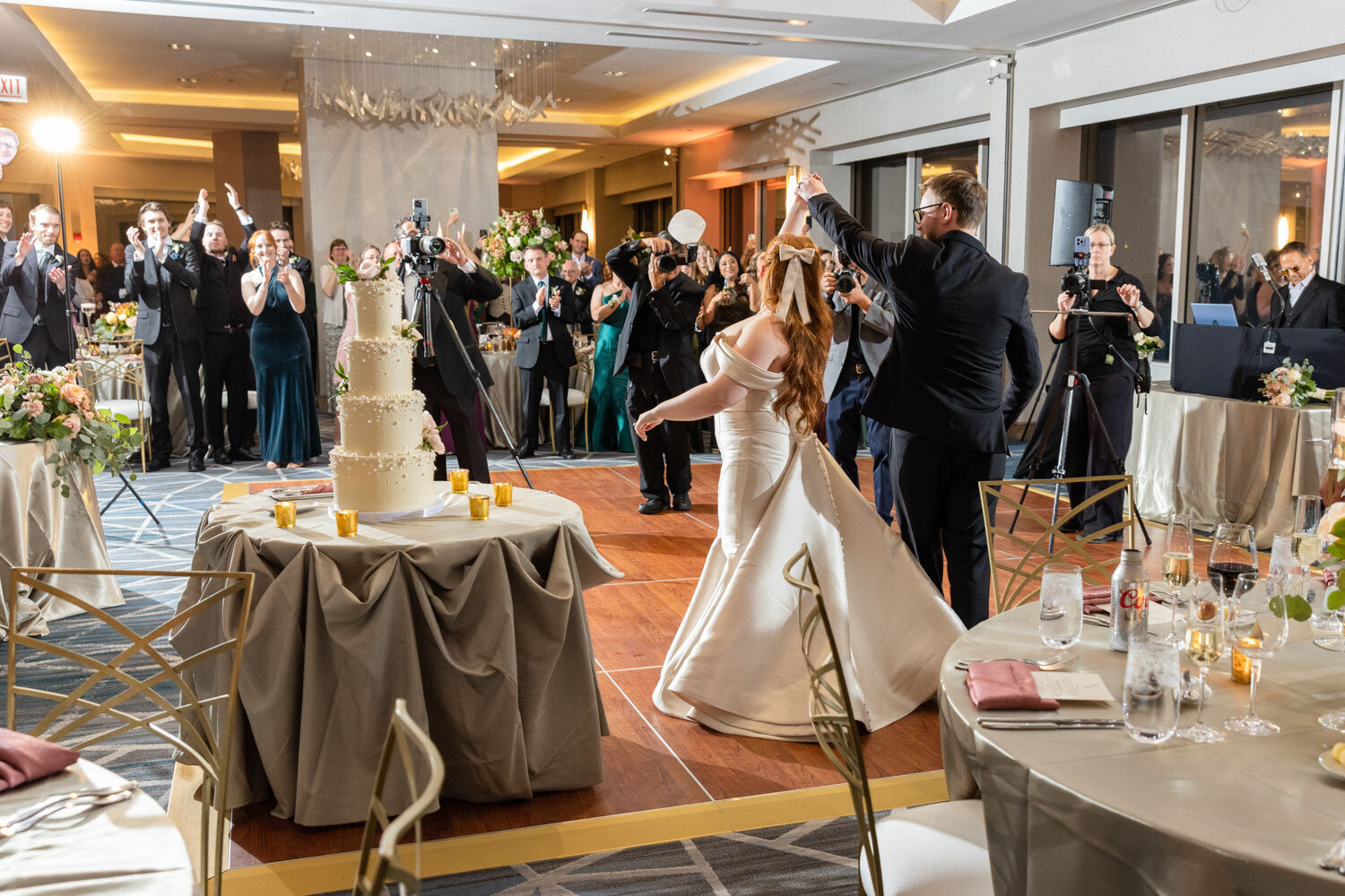 Bride and groom having their sweet dance, with the cake and guests visible