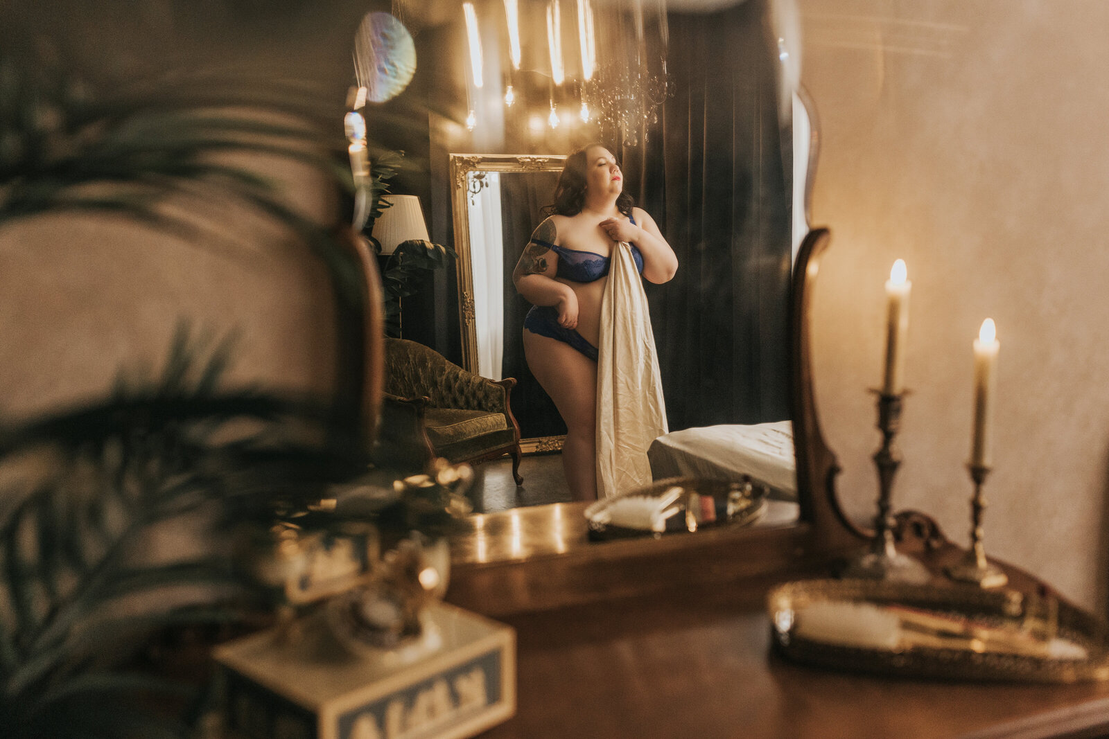 plus size model posing in boudoir photography studio in vancouver bc with a sheet and vintage decor