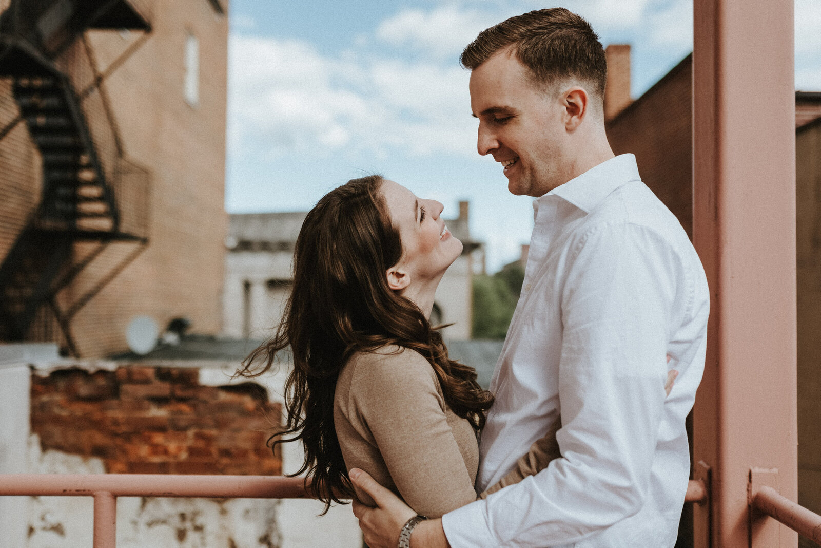 A man and woman stand facing each other on a fire escape