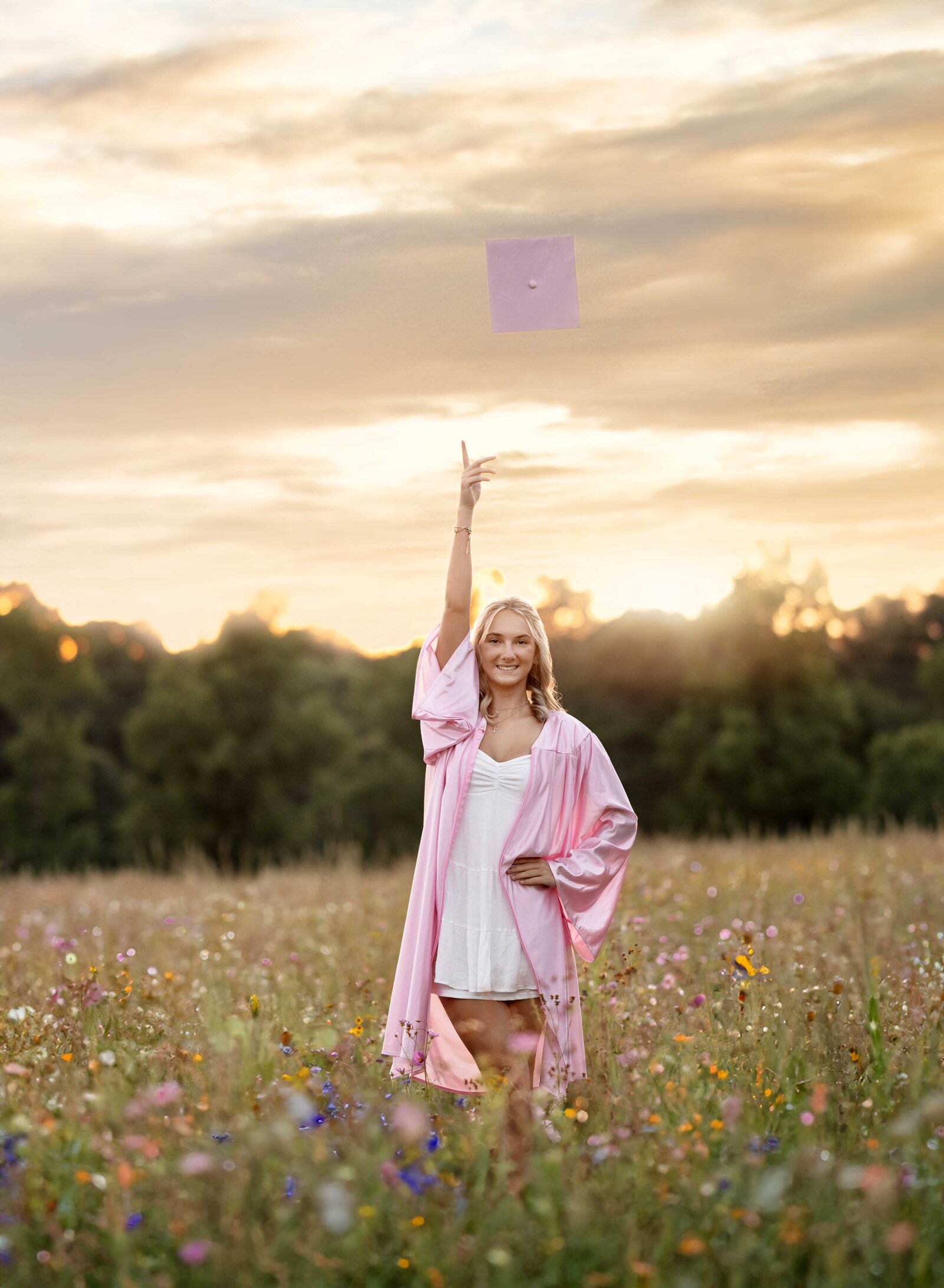 Graduation photo of girl tossing up a graduation cap in a wildflower field in Atlanta, GA. Graduation photos taken by Jenni Nikki Photography in Atlanta, GA