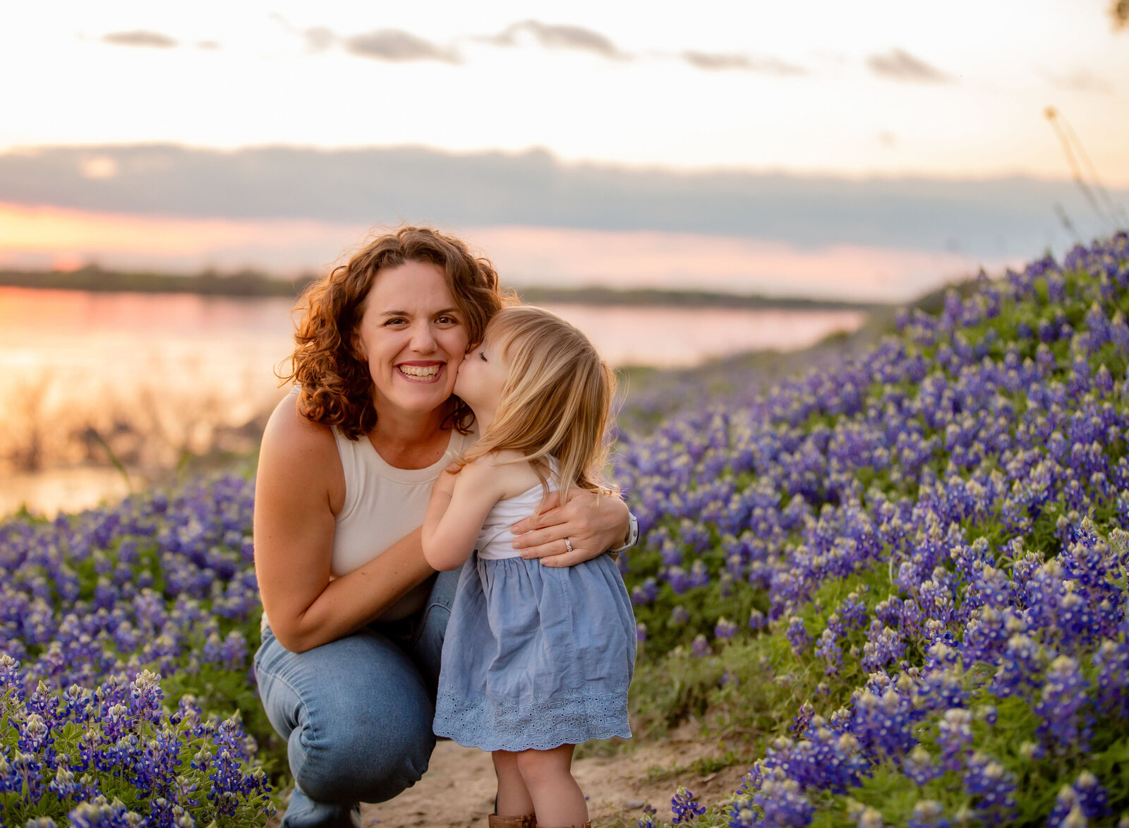 toddler kissing mom in Texas bluebonnets