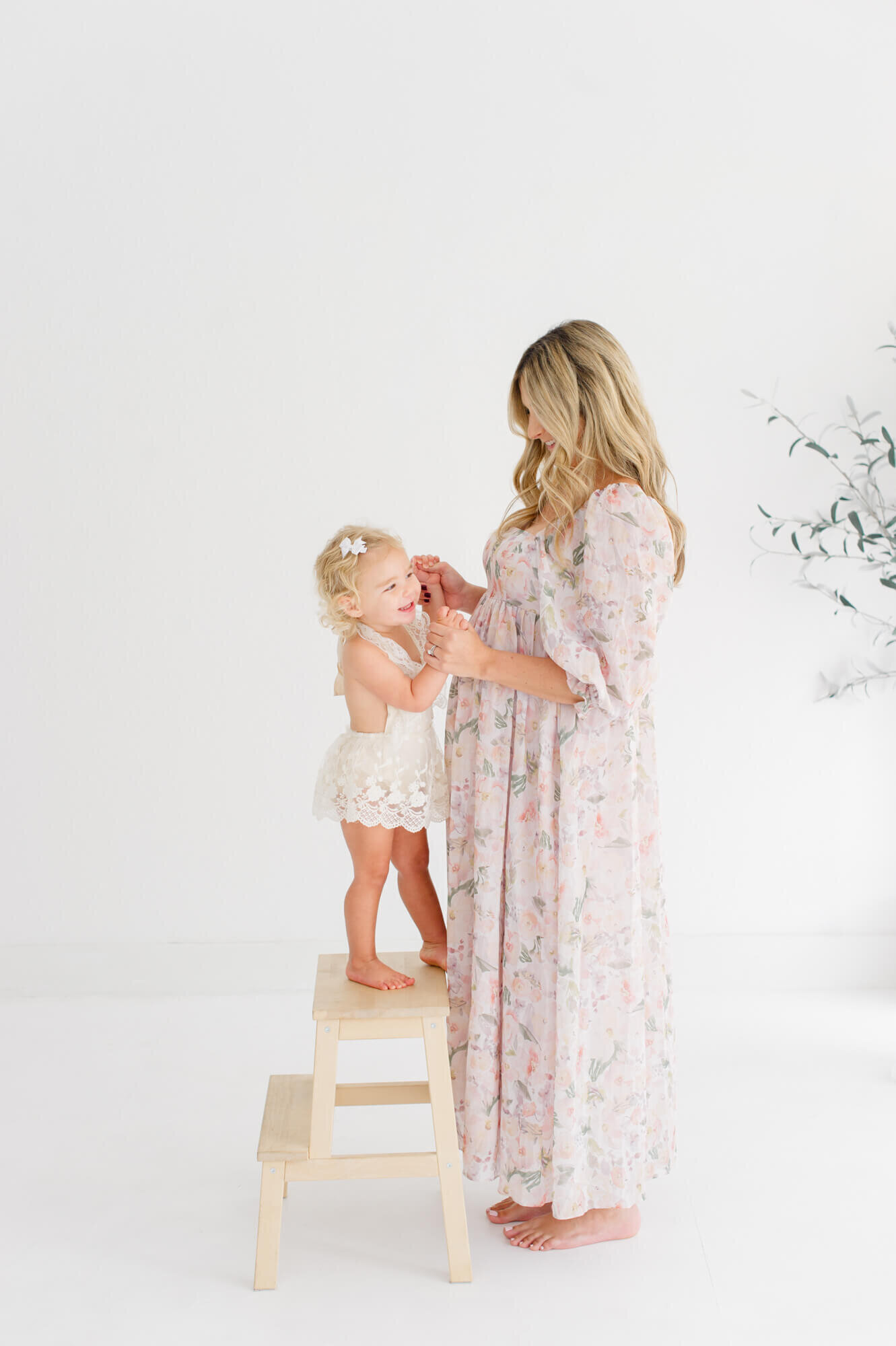 Studio session with daughter standing on wooden step stool holding her daughters hands