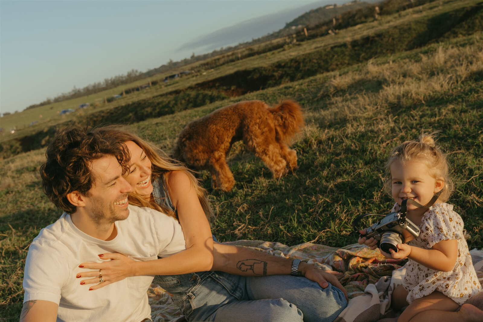 Styled Maui family photography session on a cliffside, capturing candid laughter and connection in denim and neutral tones.