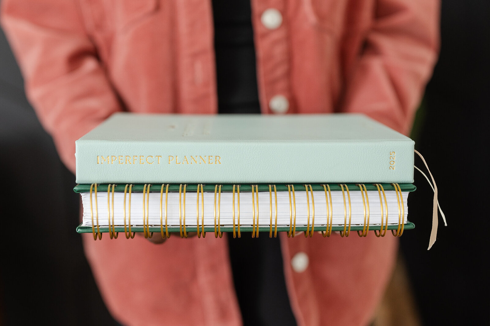 a woman holds her planners in her hands
