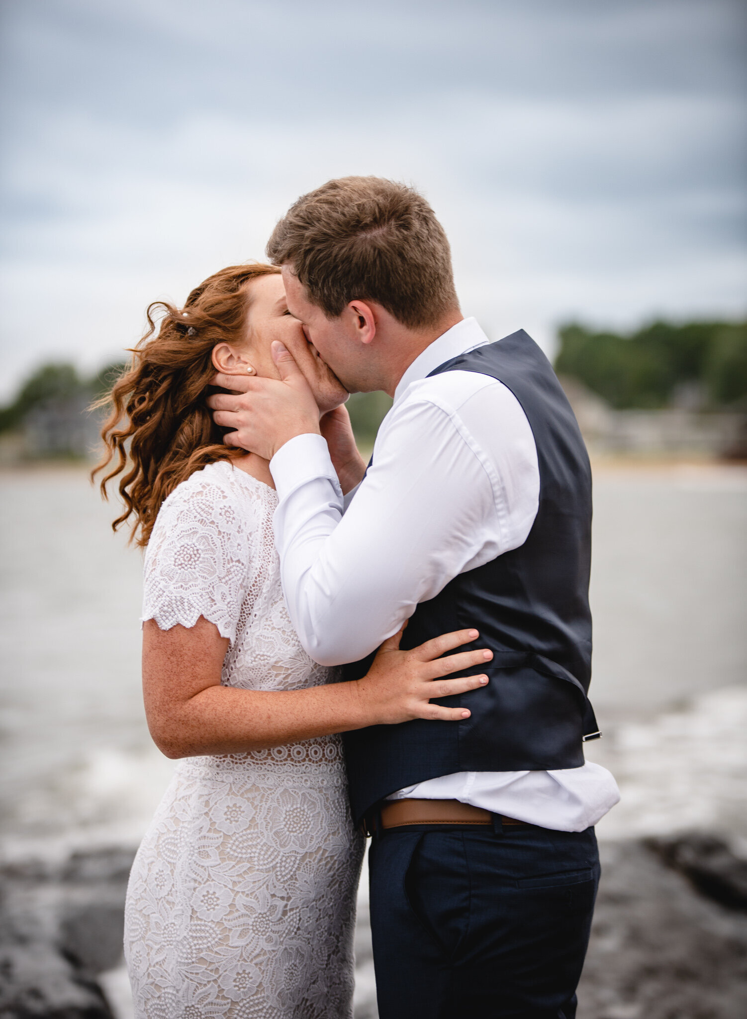 wedding couple kissing on rocky beach