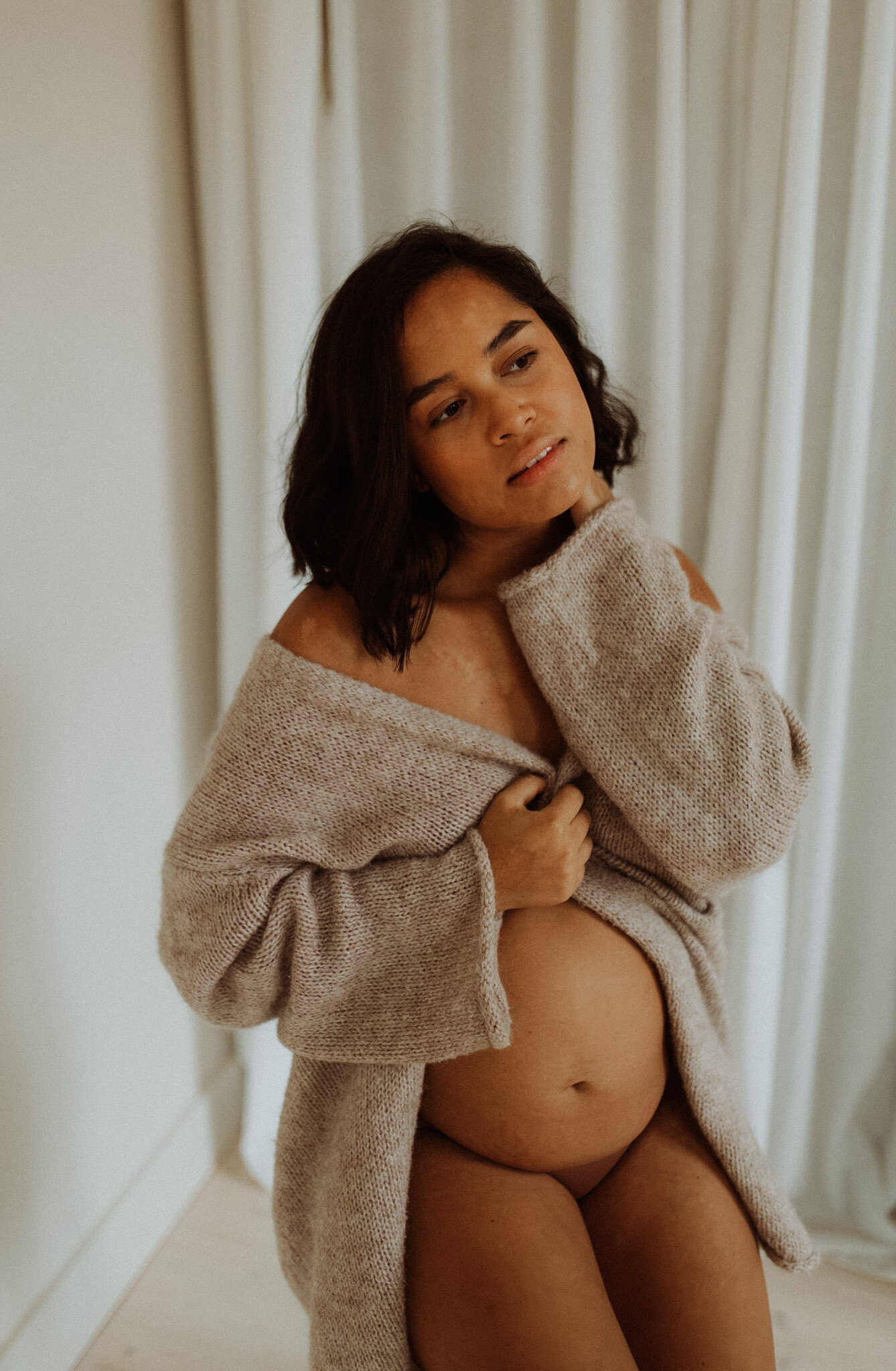 en gravid mamma sitter på en pall i en kofta